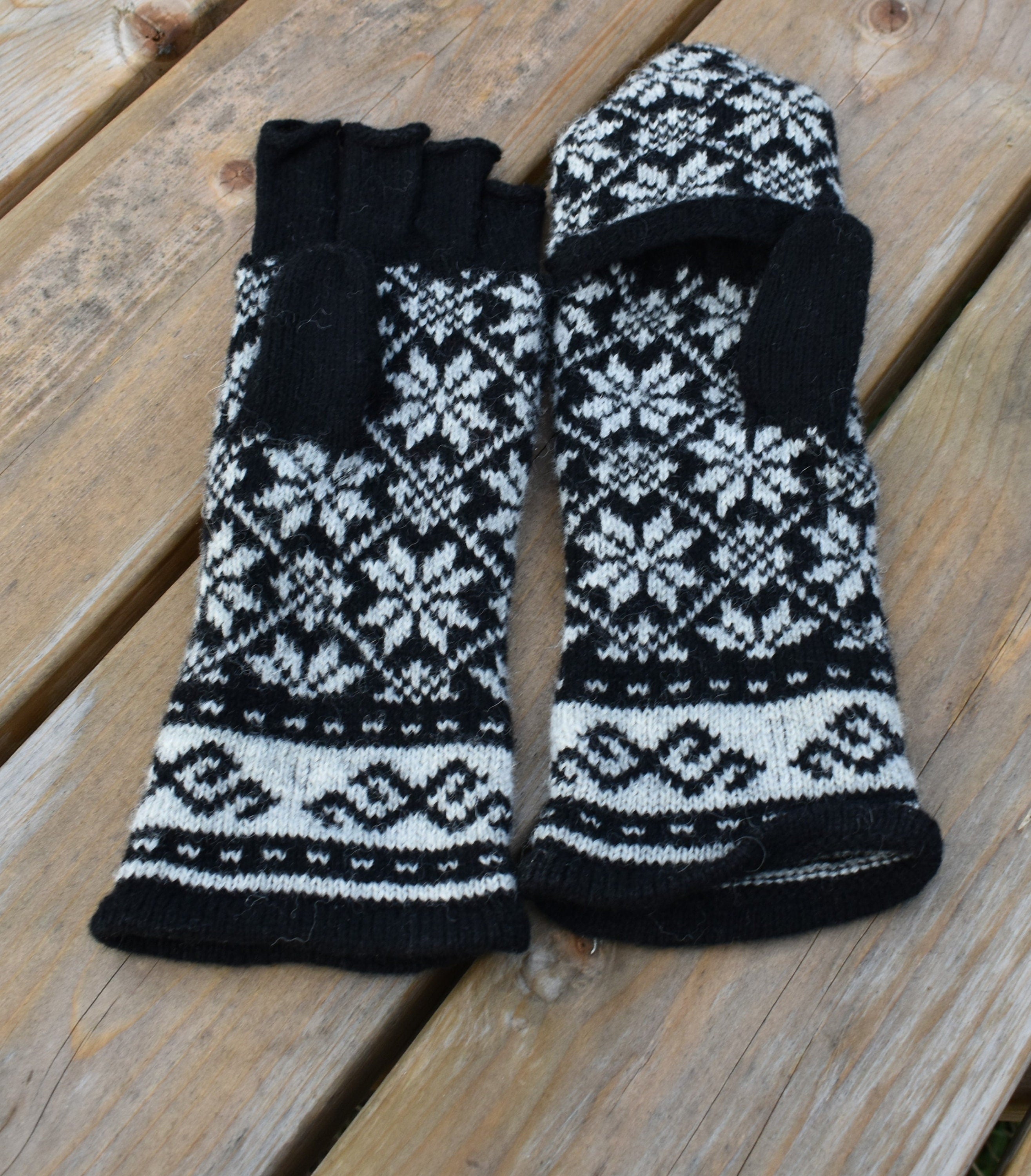 Pair of black and white patterned gloves on a wooden surface