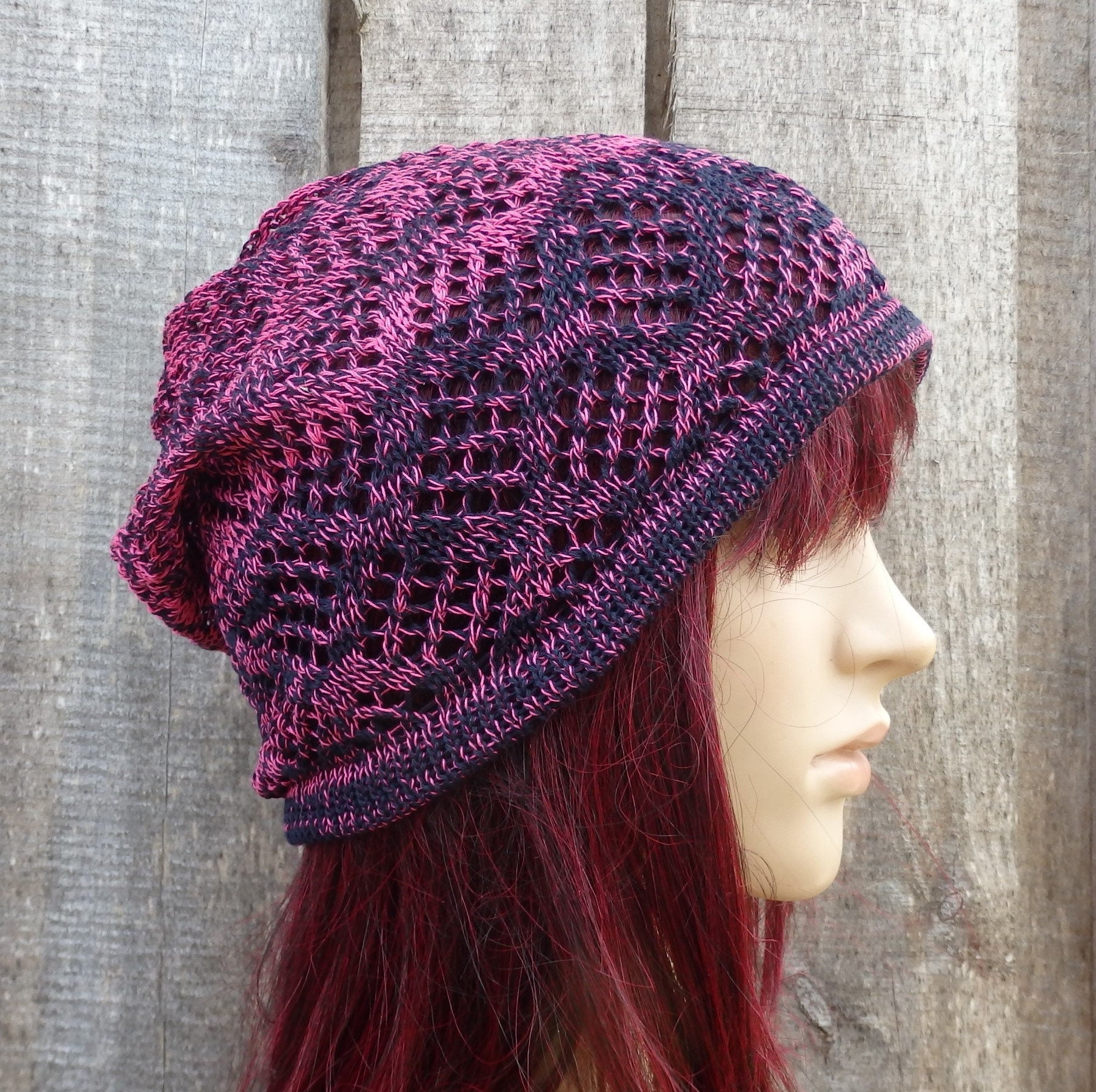 Knitted purple and pink hat on a mannequin head against a wooden background