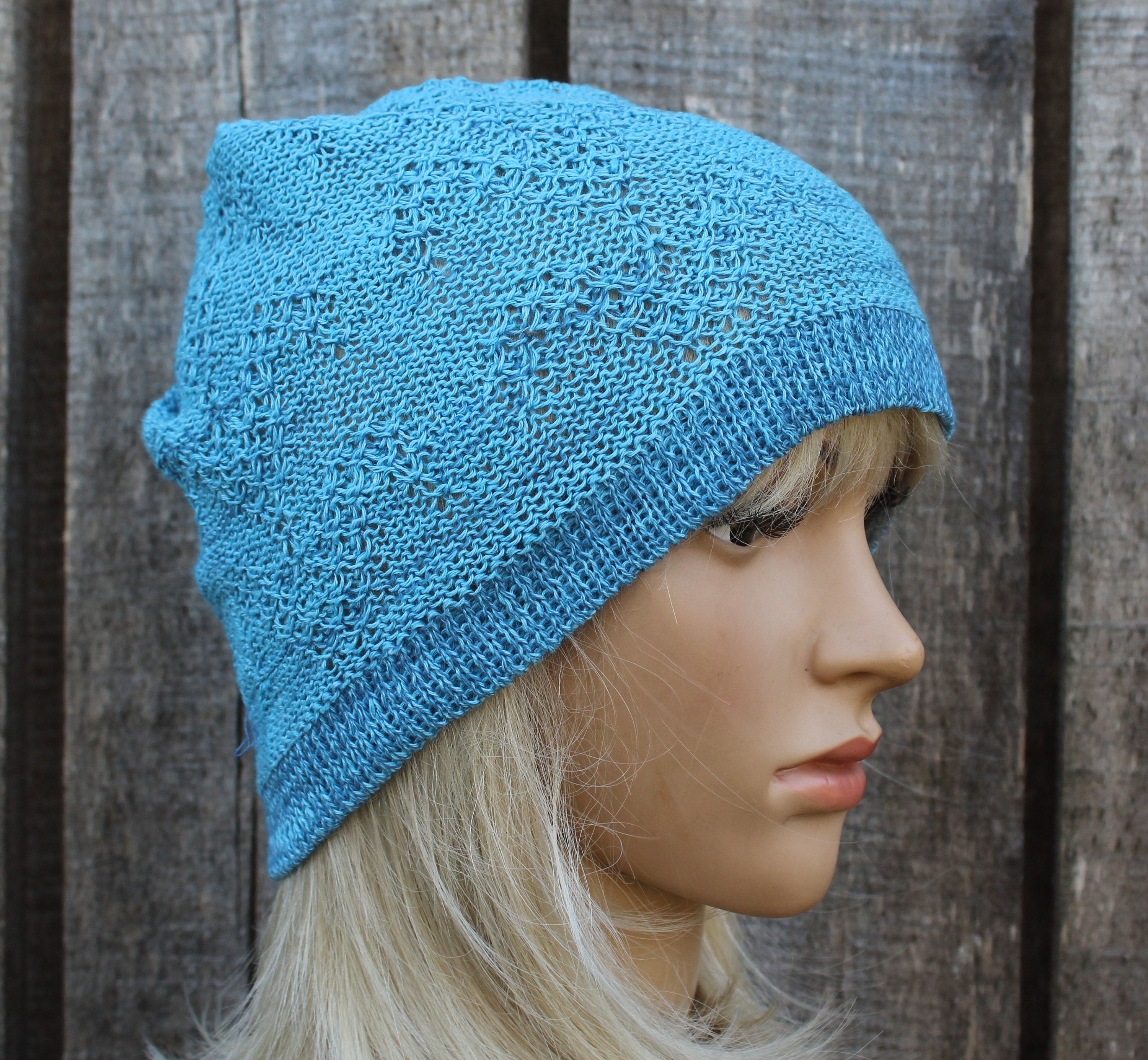 Blue knitted hat worn by a mannequin against a wooden background