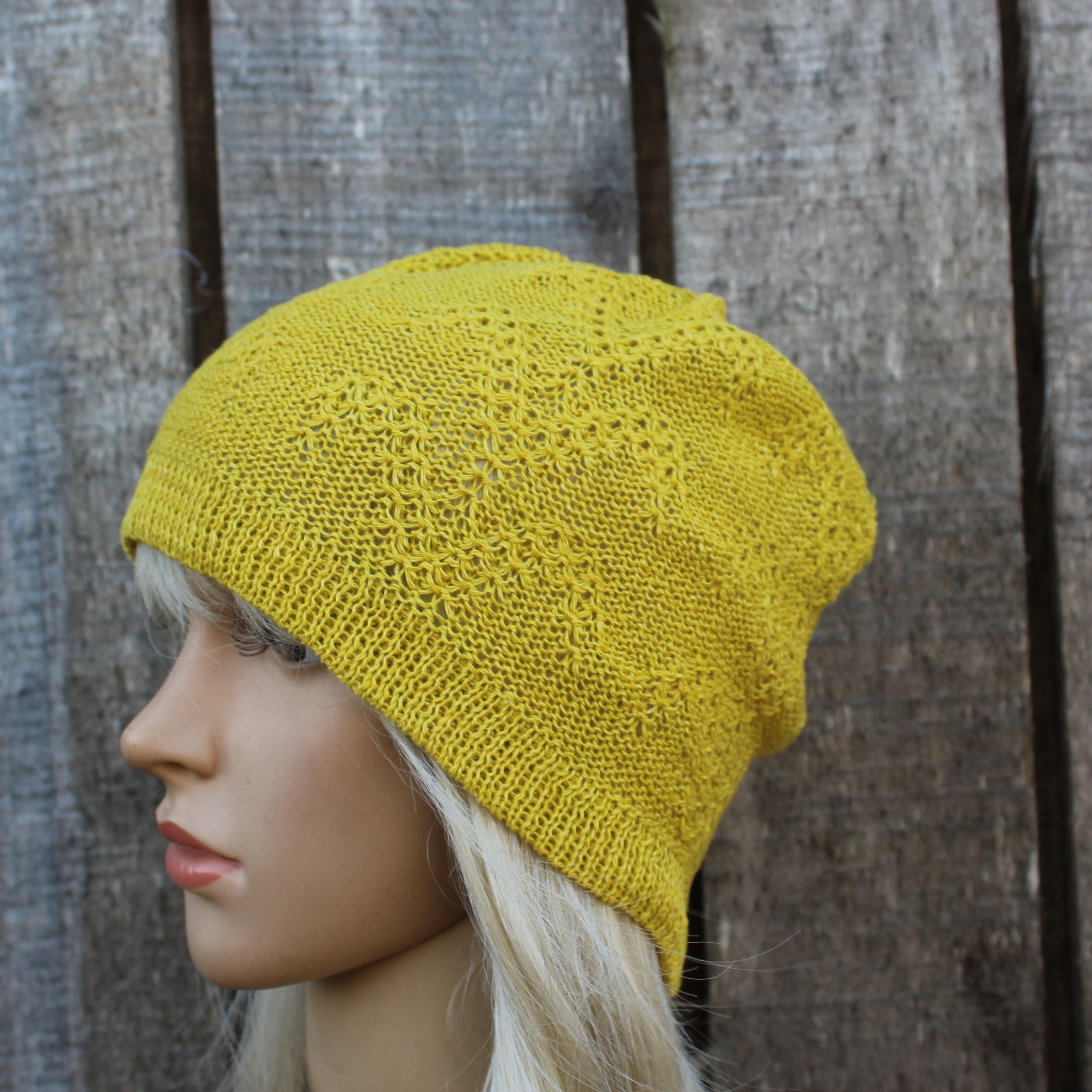 Yellow knitted beanie on a mannequin head against a wooden background