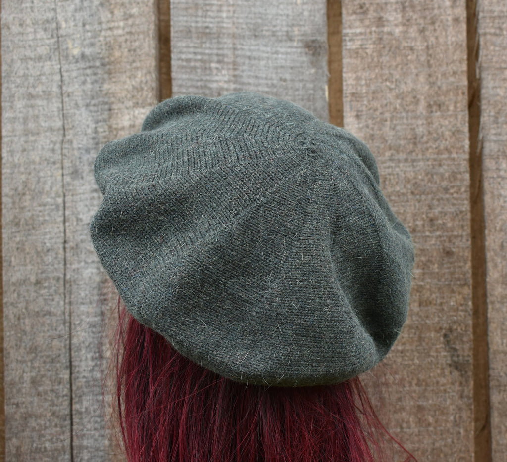 Grey knit beanie with red feathers on a wooden background