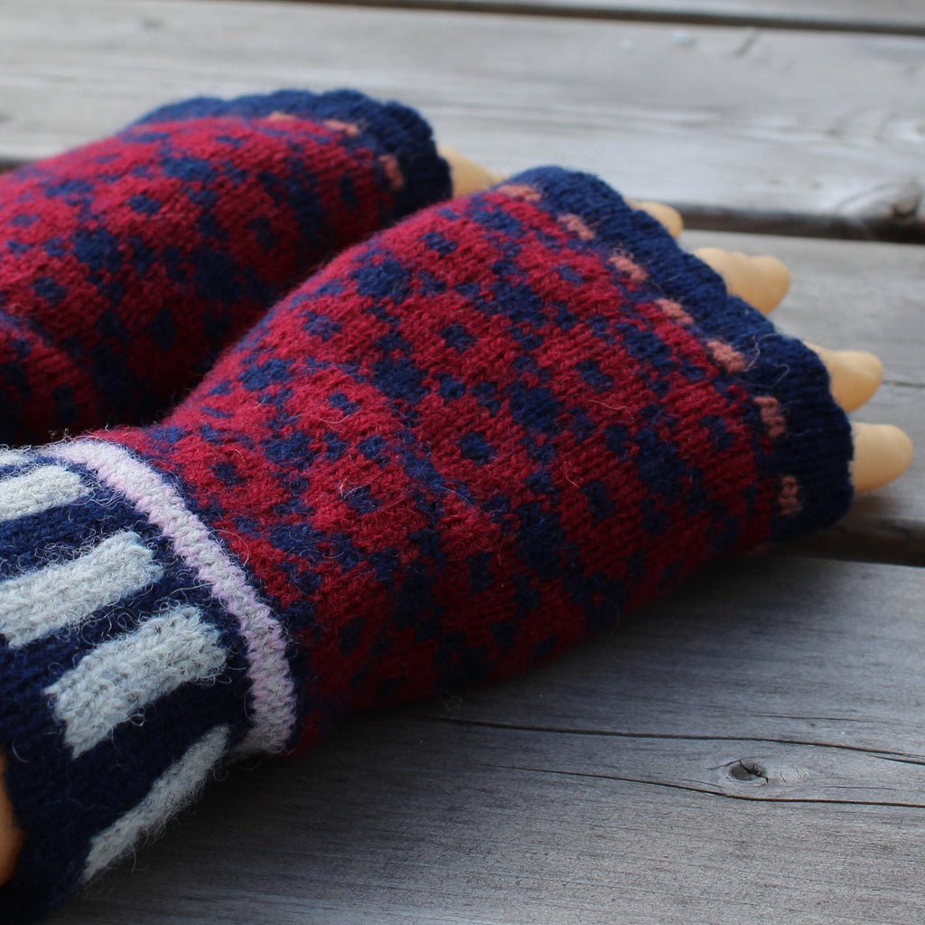 Pair of blue and red patterned fingerless gloves on a wooden surface