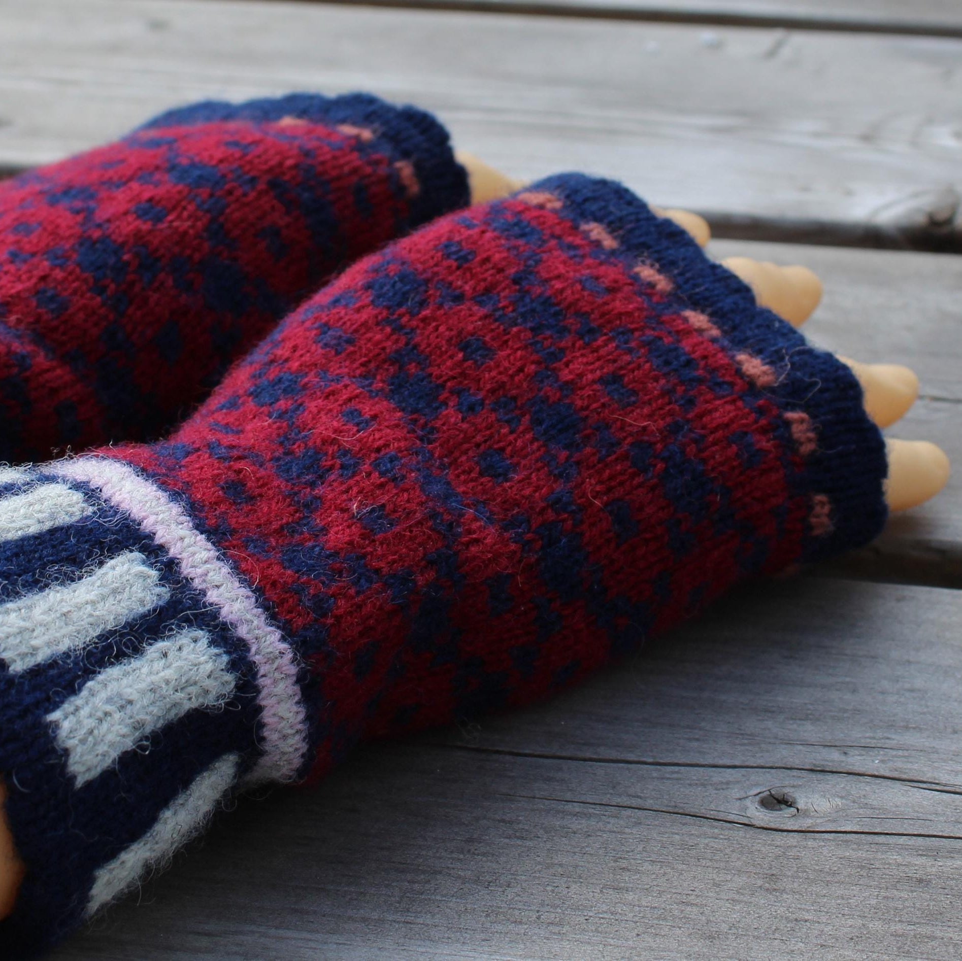 Pair of blue and red patterned fingerless gloves on a wooden surface