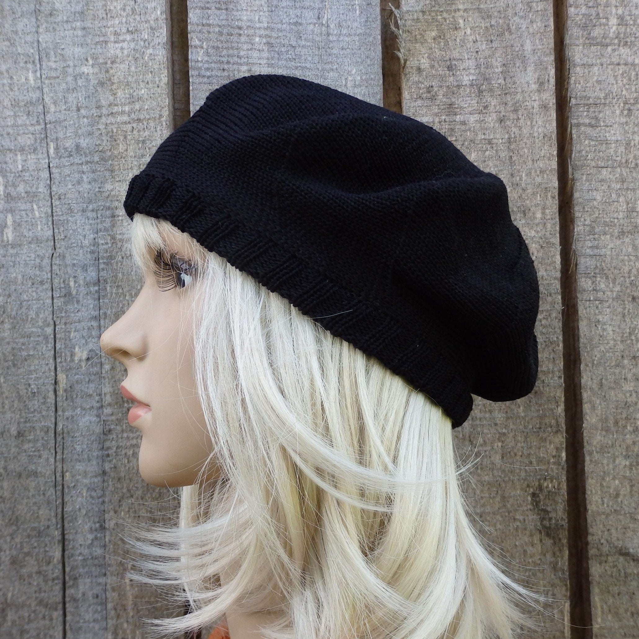 Black beanie on a mannequin head with blonde hair against a wooden background
