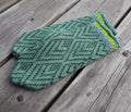 Green knitted mitten with a geometric pattern on a wooden surface