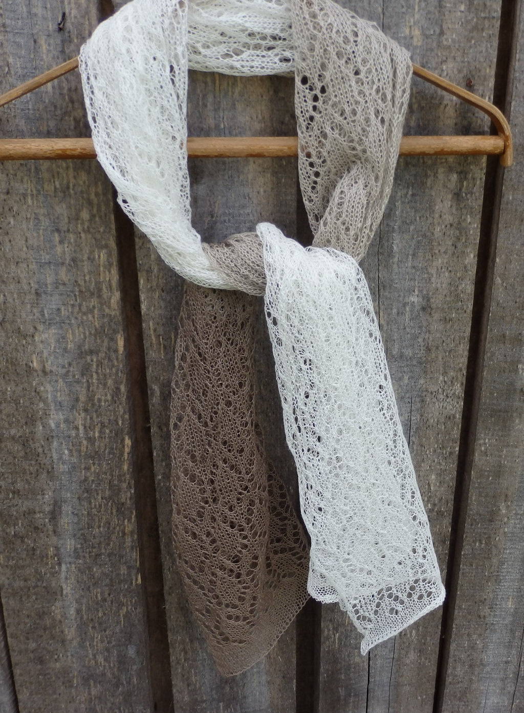 Lace scarf draped over a wooden hanger against a rustic wooden background