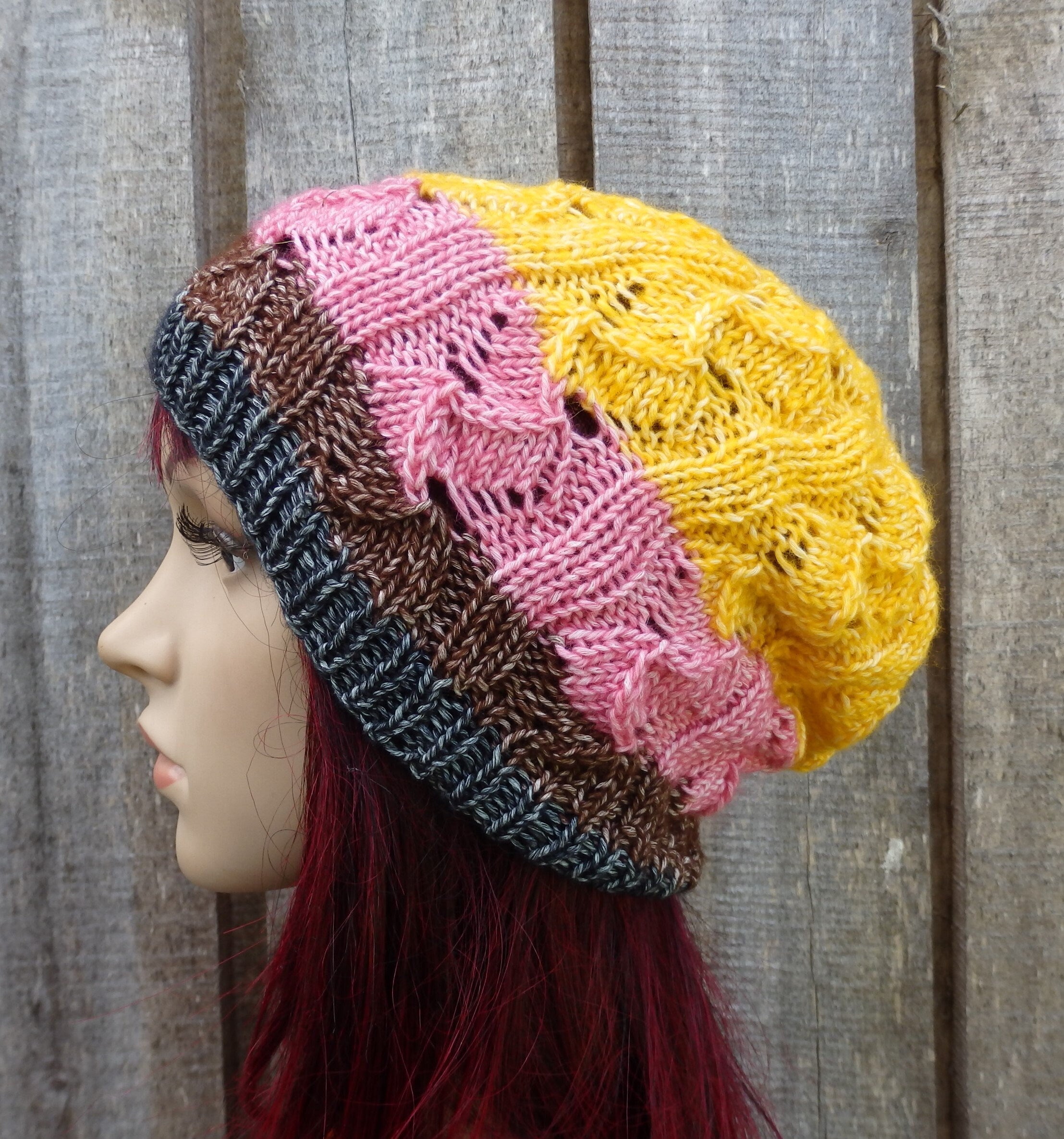 Multicolored knitted hat on a mannequin head against a wooden background
