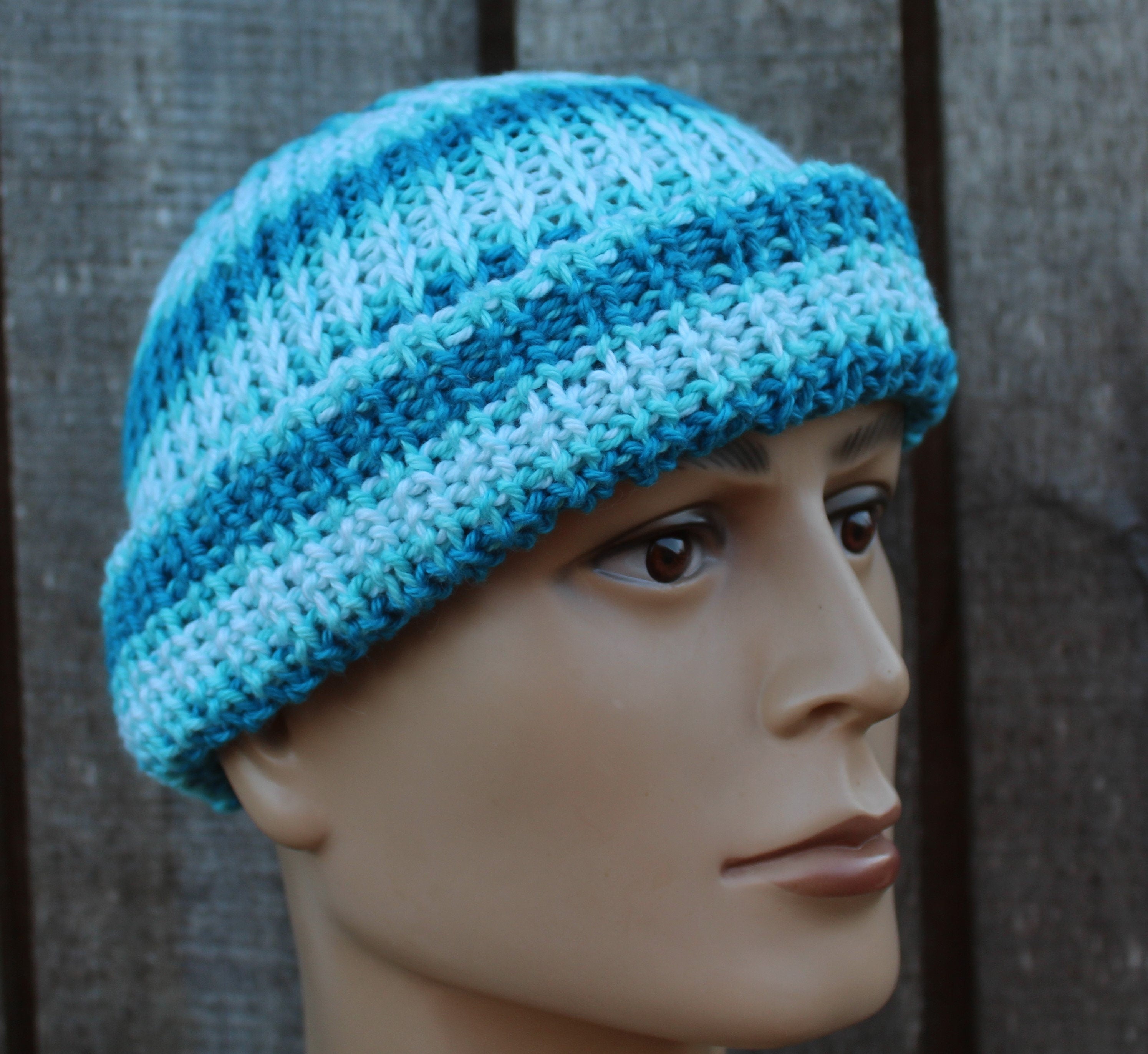 Blue knitted beanie on a mannequin head against a wooden background