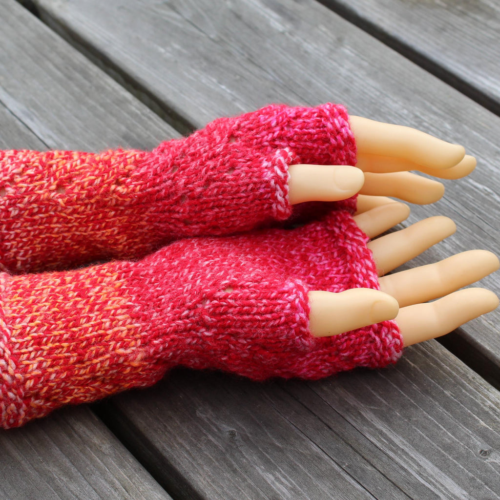 Red knitted fingerless gloves on a mannequin hand against a wooden background