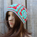 Mannequin head wearing a colorful crochet beanie against a wooden background