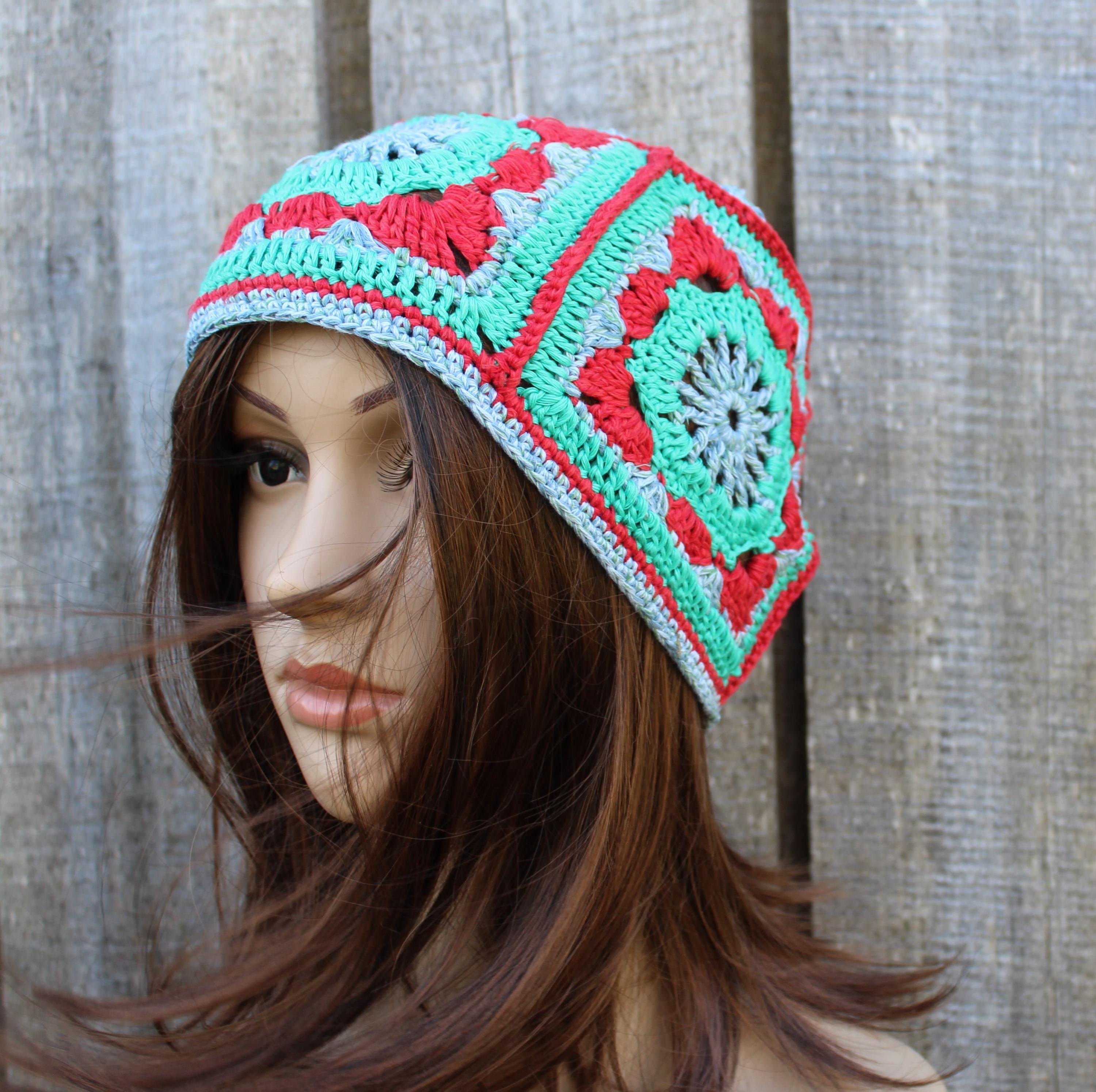 Mannequin head wearing a colorful crochet beanie against a wooden background