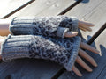 Pair of gray knitted fingerless gloves on a wooden surface