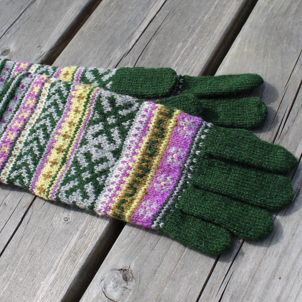 Pair of green gloves with colorful pattern on a wooden surface