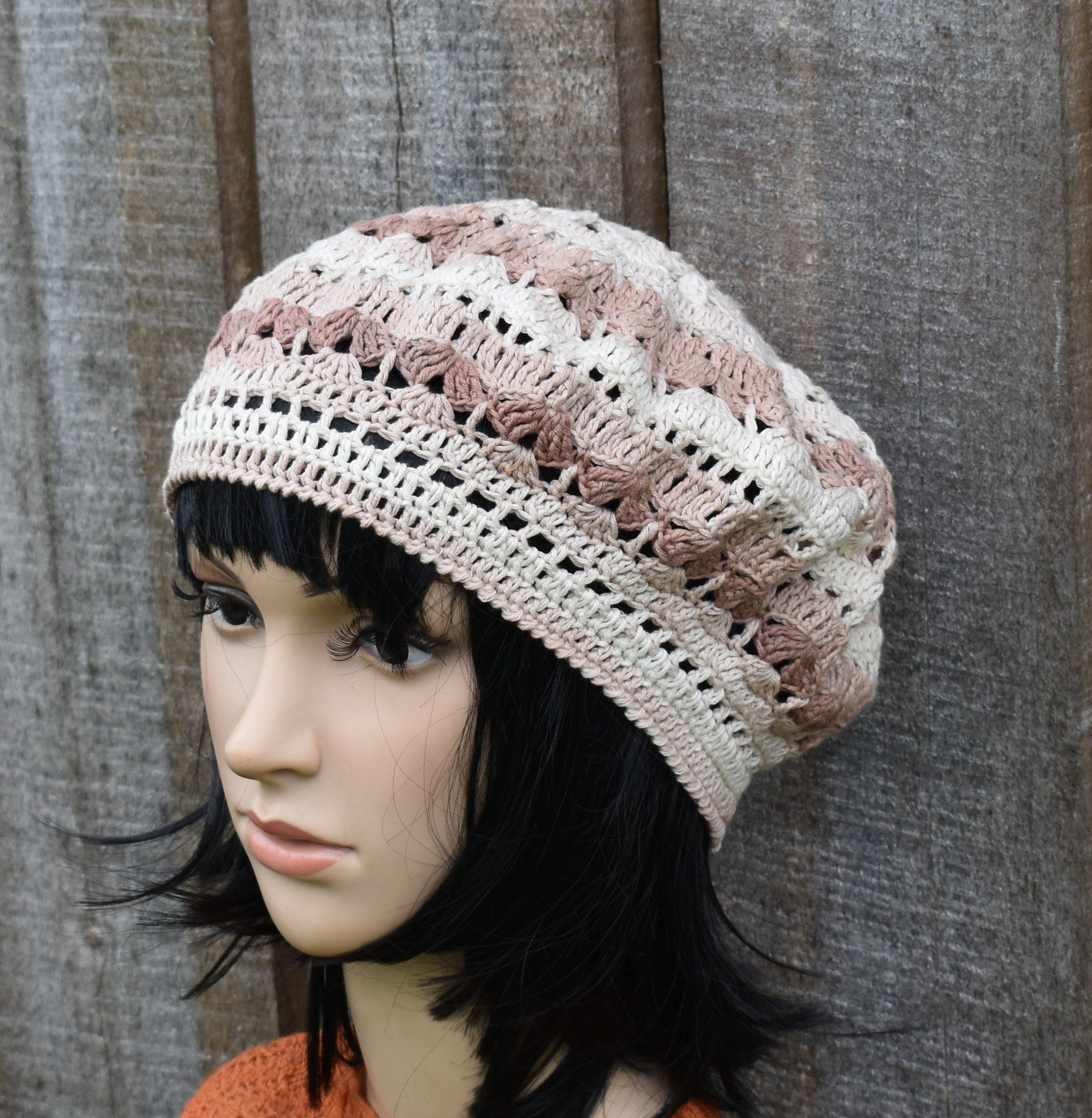 Mannequin head wearing a crocheted beanie with a textured background