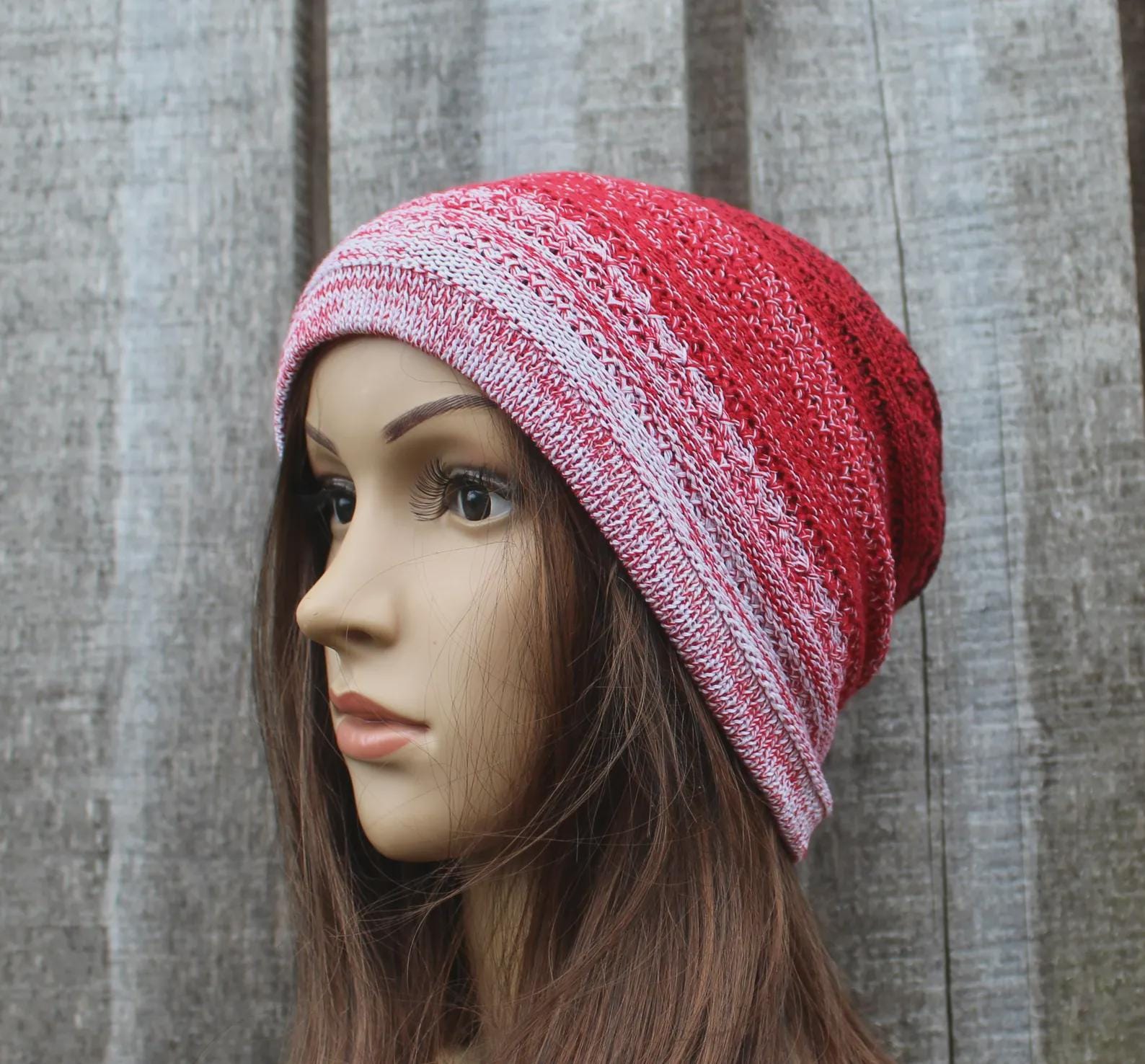 Mannequin head wearing a red and white striped knit beanie against a wooden background