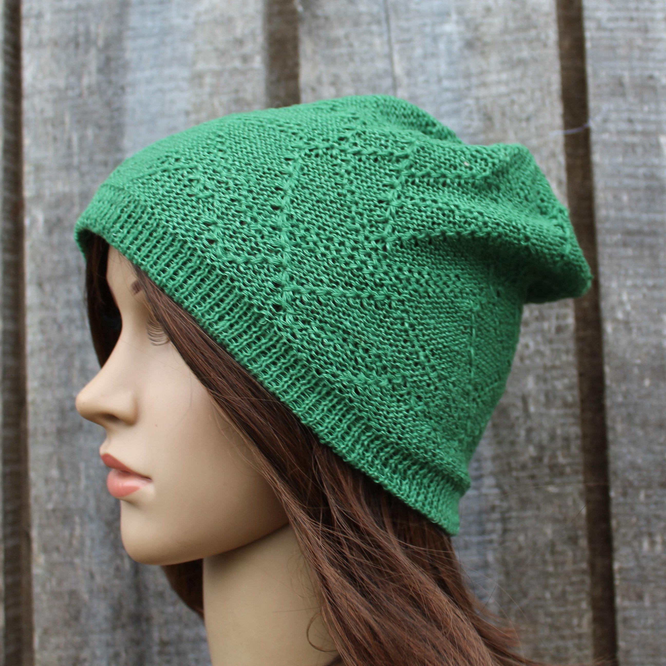 Green summer beanie on a mannequin head against a wooden panel background
