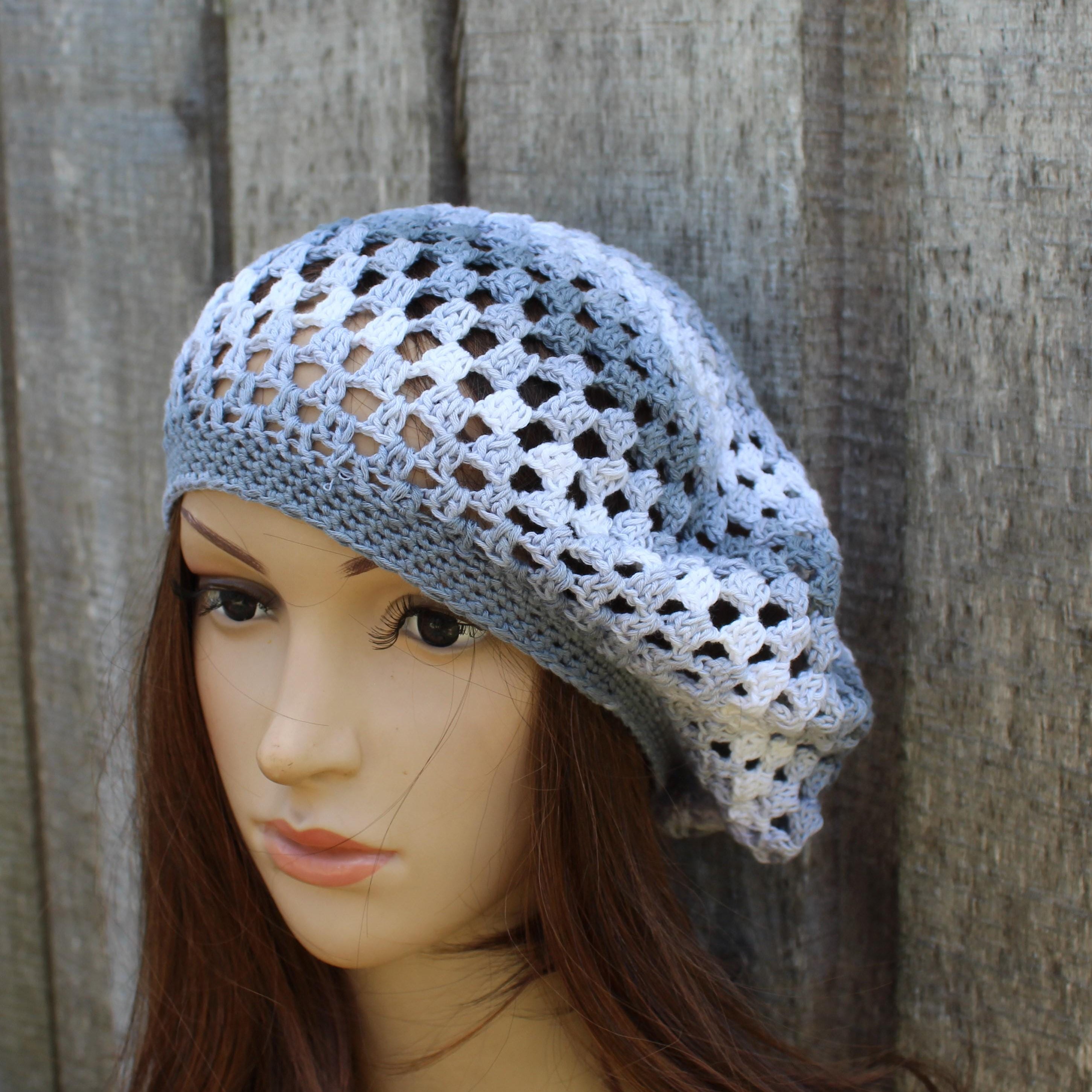 Mannequin head wearing a light blue crochet hat against a wooden background