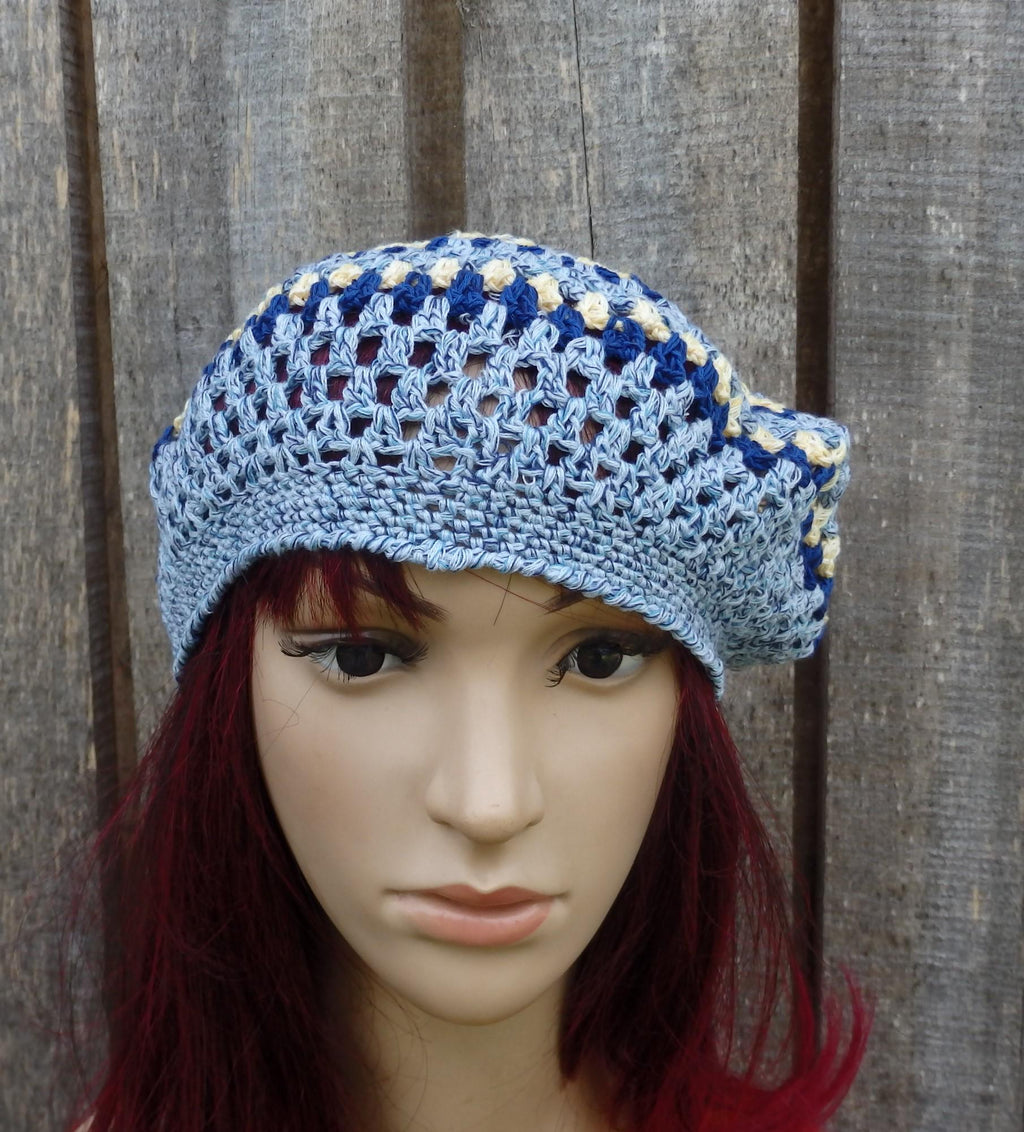 Blue and white crocheted beret on a mannequin head against a wooden background