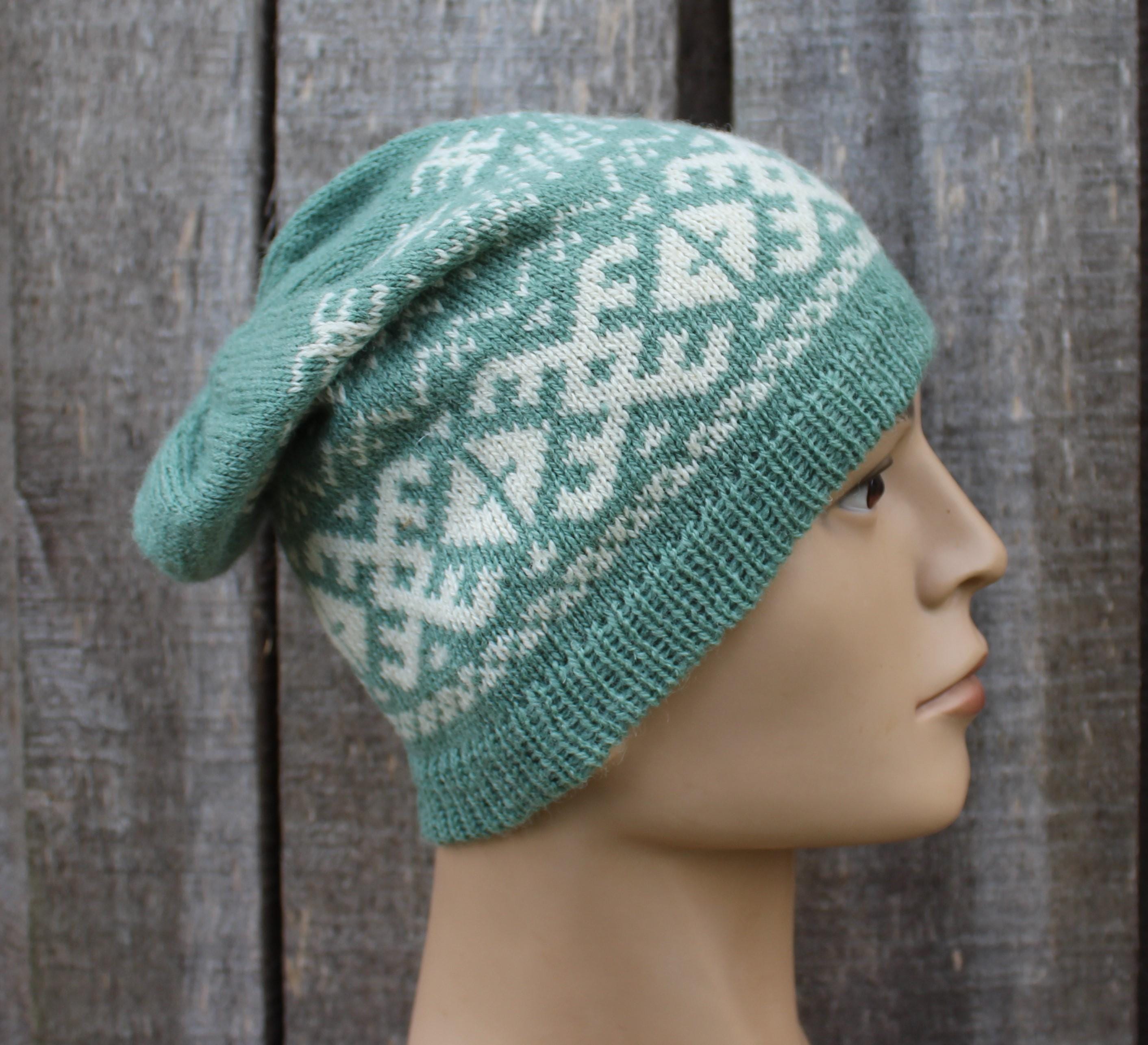 Green knitted hat with a pattern on a mannequin head against a wooden background