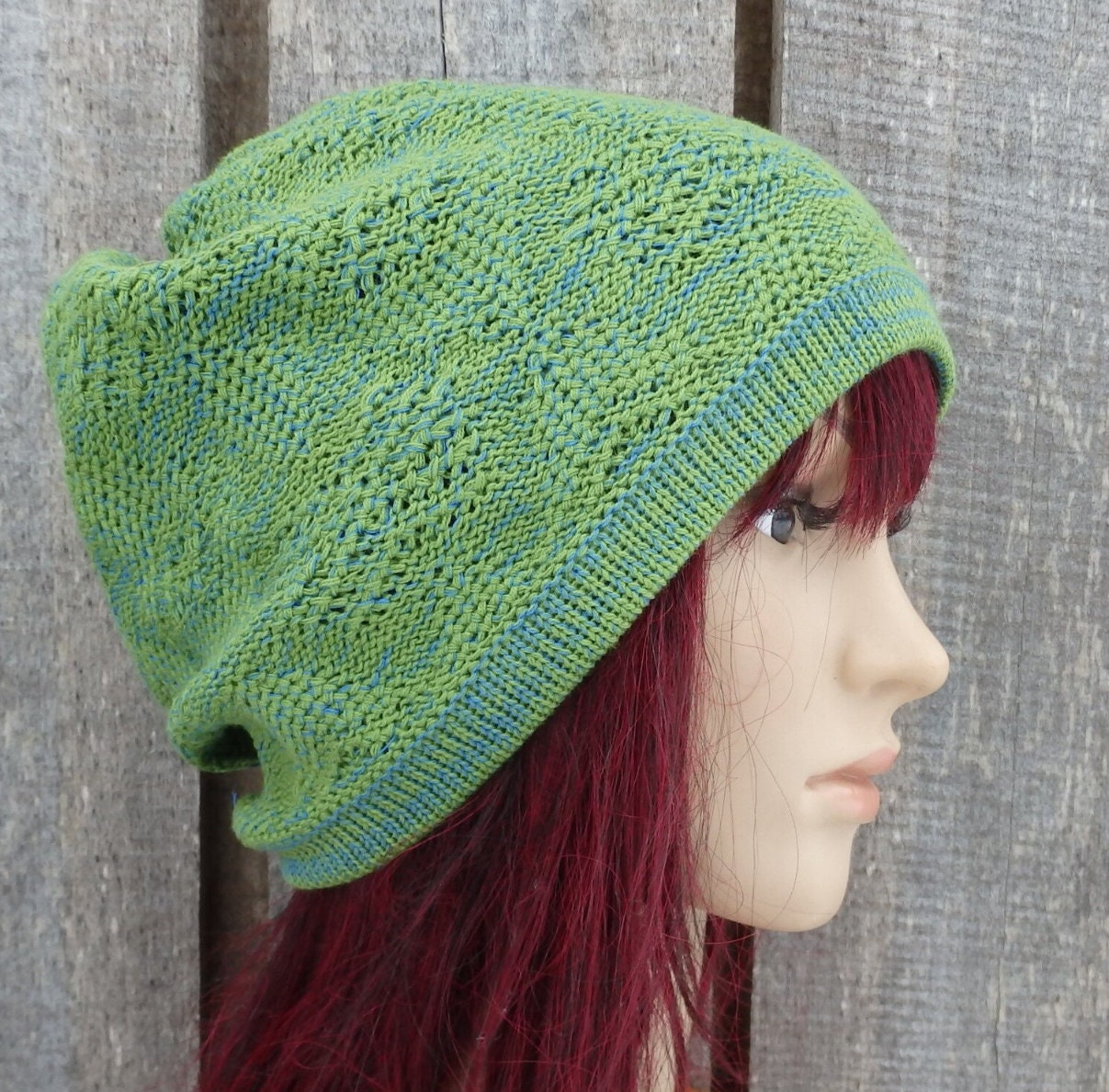 Green knitted beanie on a mannequin head against a wooden background
