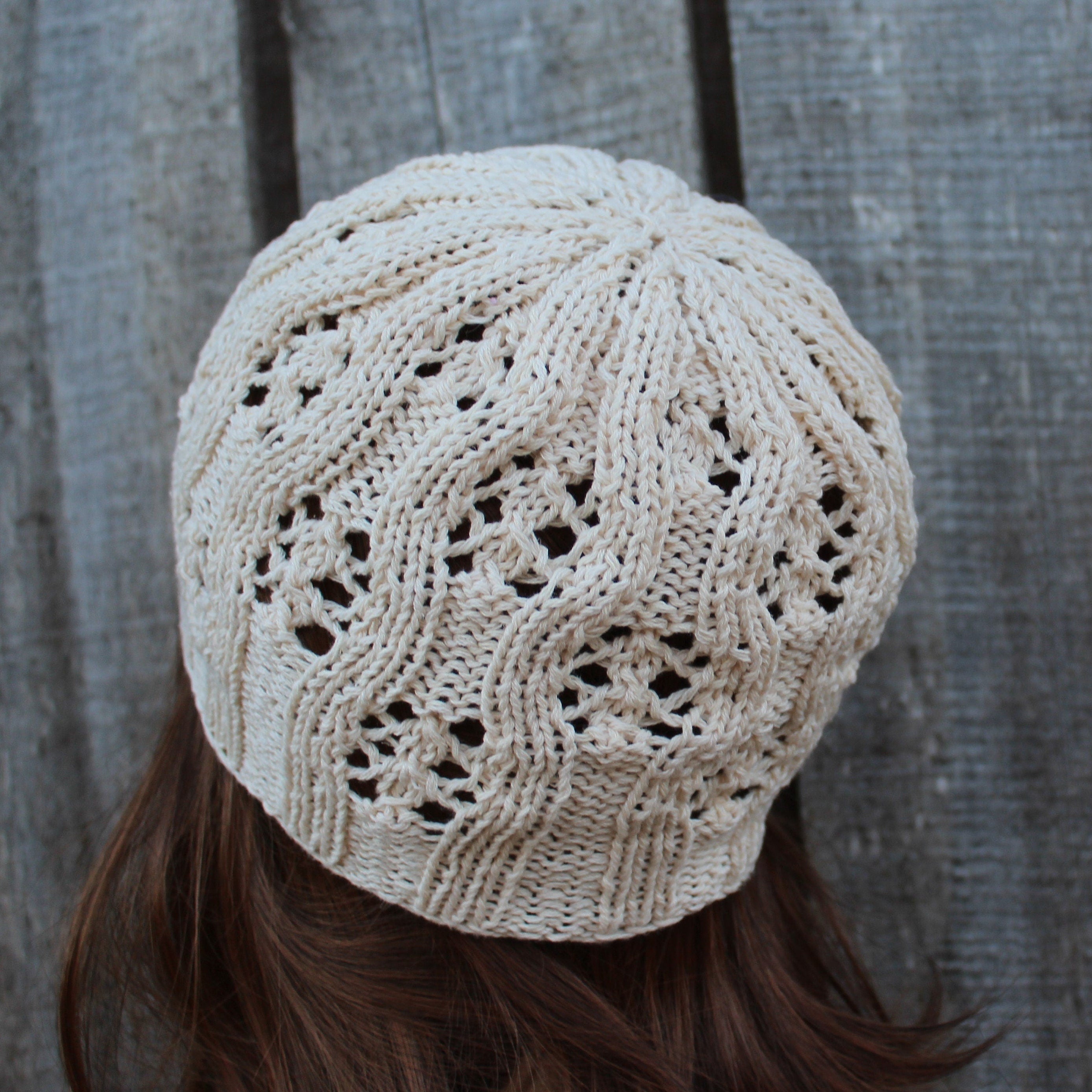 Beige knitted hat worn by a person with a wooden background