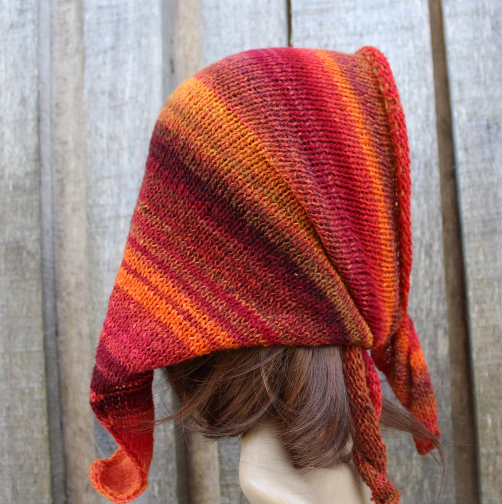 Knitted hood with red and orange gradient on a wooden background