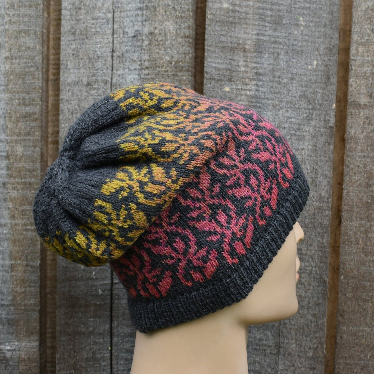 Knitted hat with a pattern on a mannequin head against a wooden background