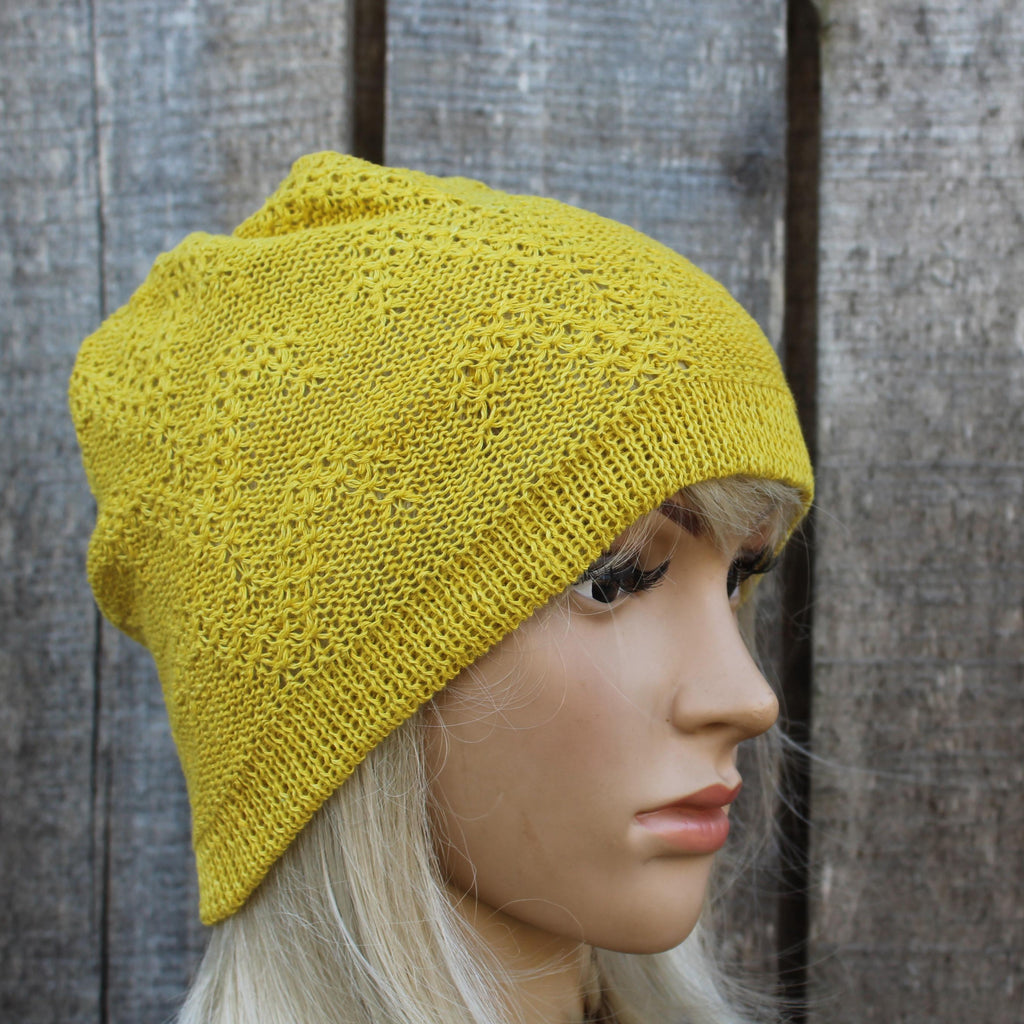 Yellow knitted beanie on a mannequin head against a wooden background