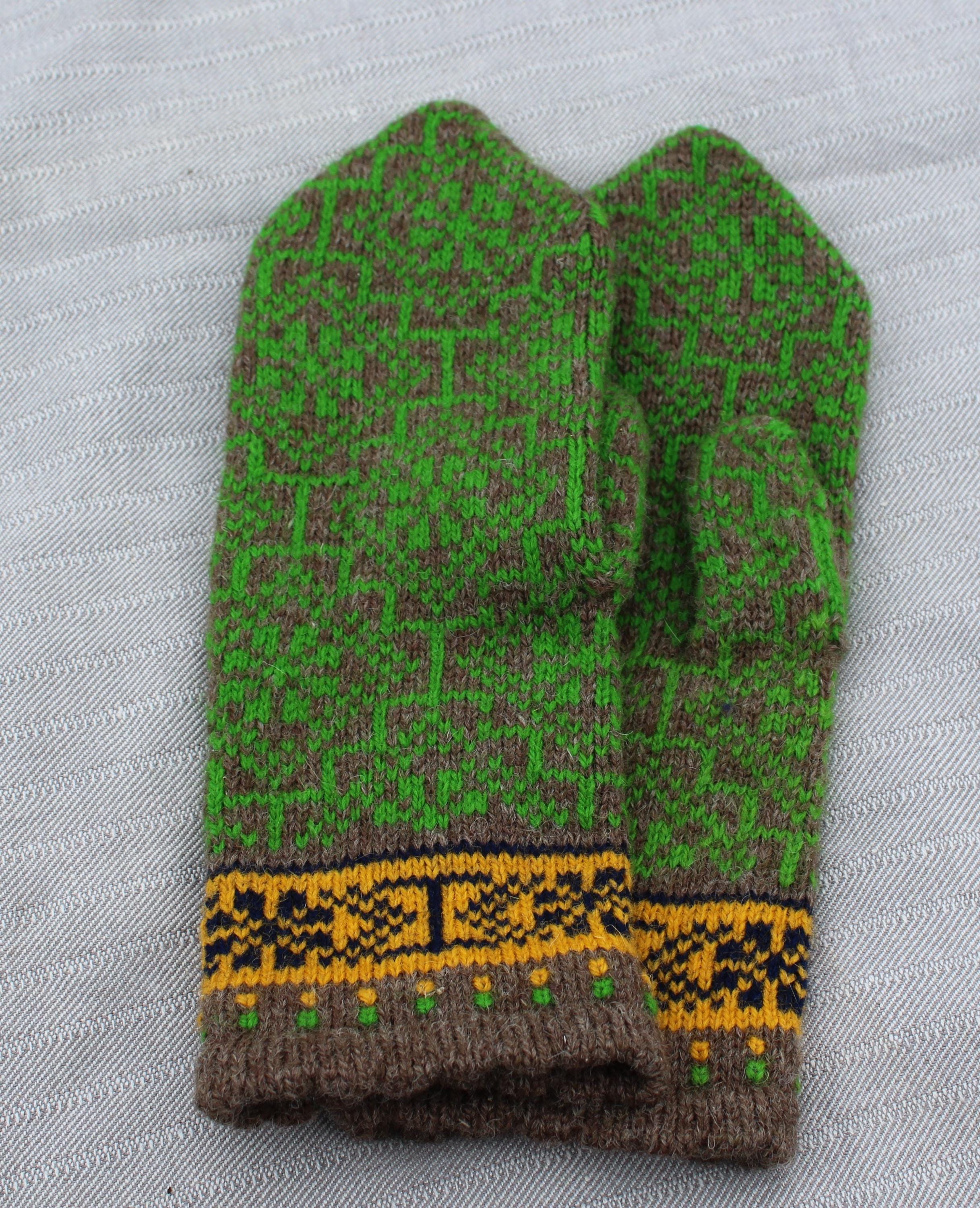 Green and brown knitted mitten with a yellow pattern on a white background