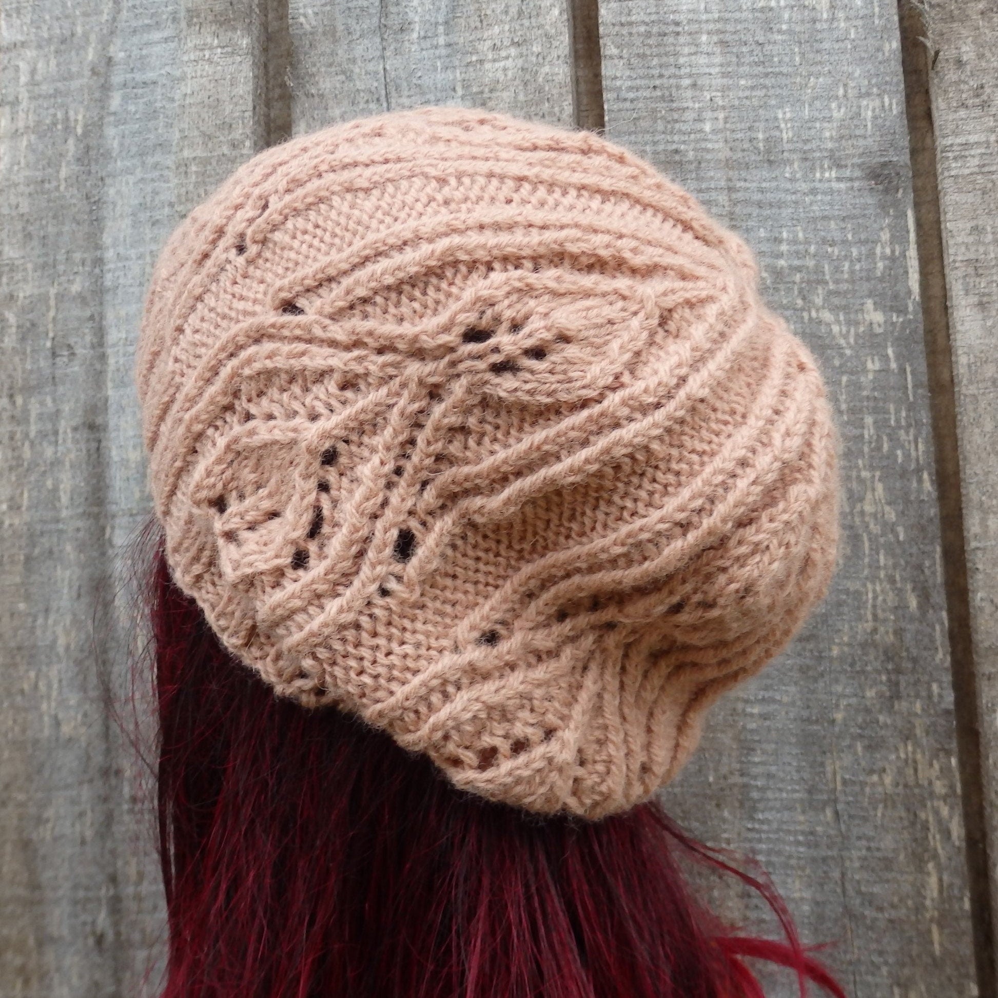 Knitted beige beanie with intricate pattern on a wooden surface