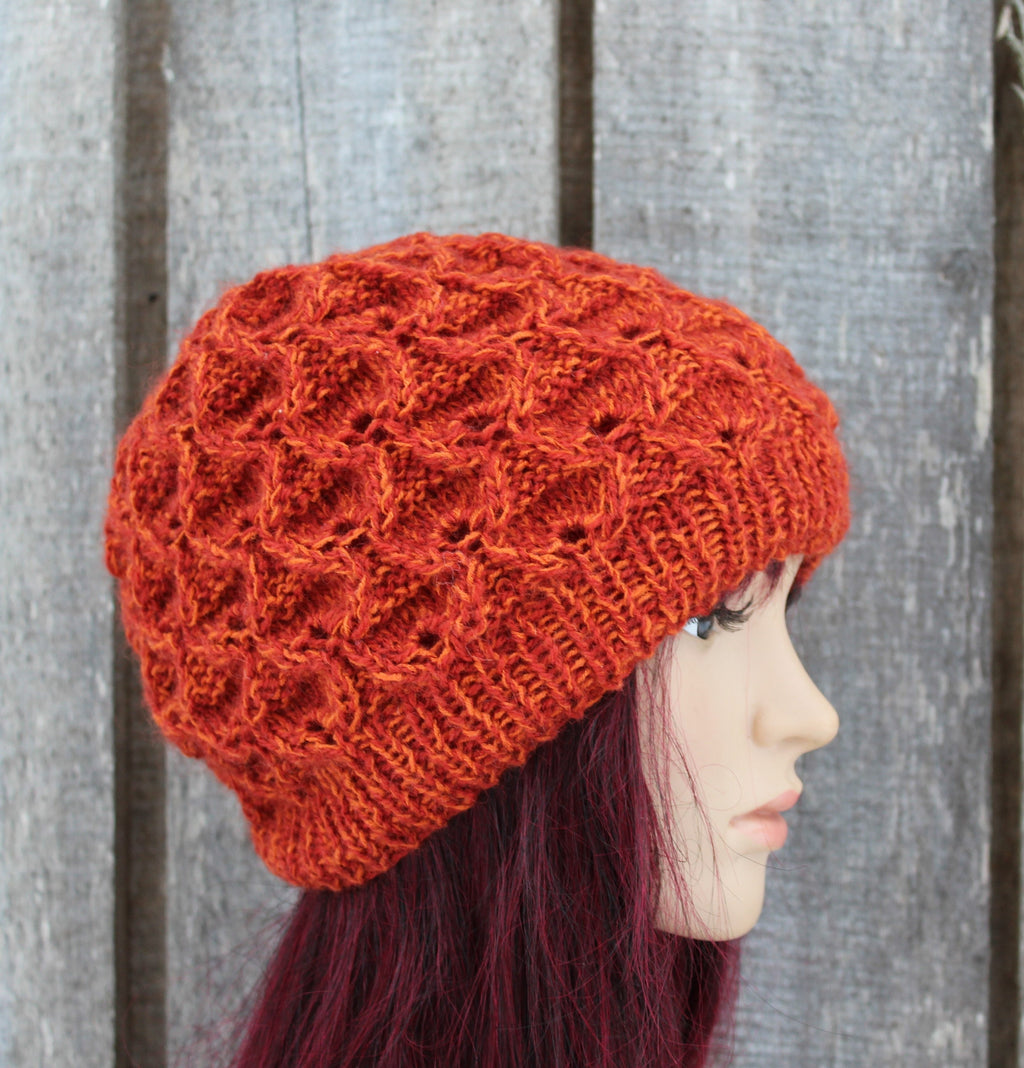 Orange knitted hat on a mannequin head against a wooden background