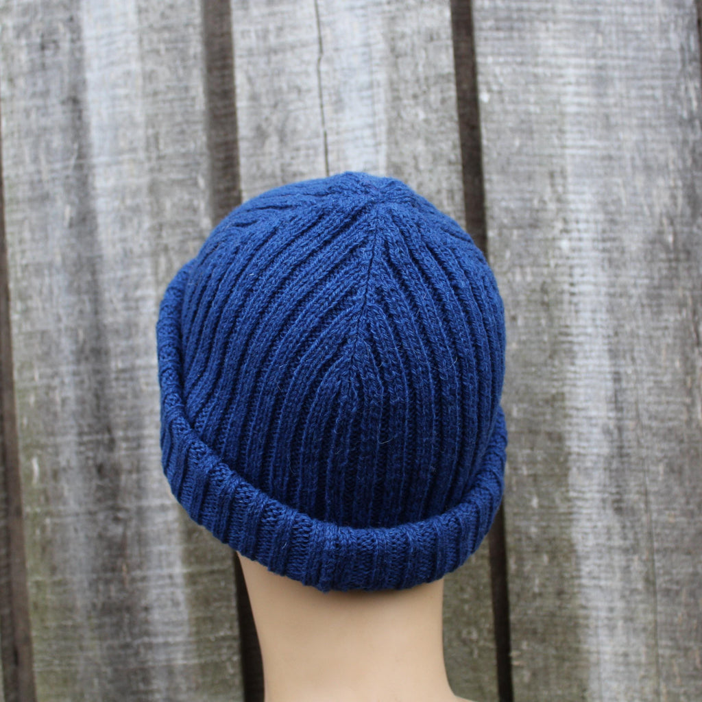 Blue knitted beanie on a mannequin head against a wooden background