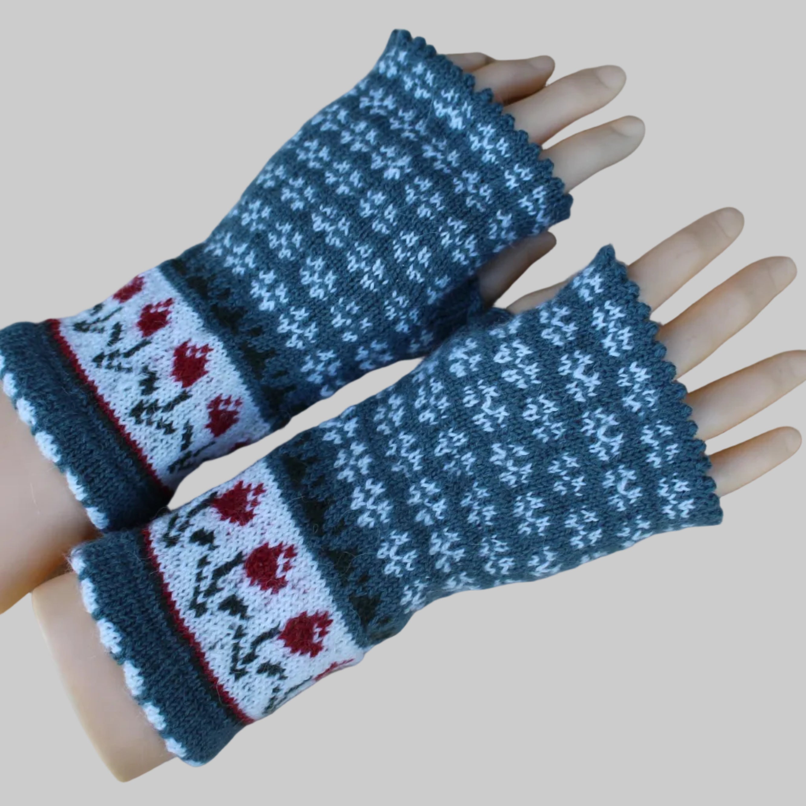 Pair of knitted wrist warmers with floral pattern on a wooden surface