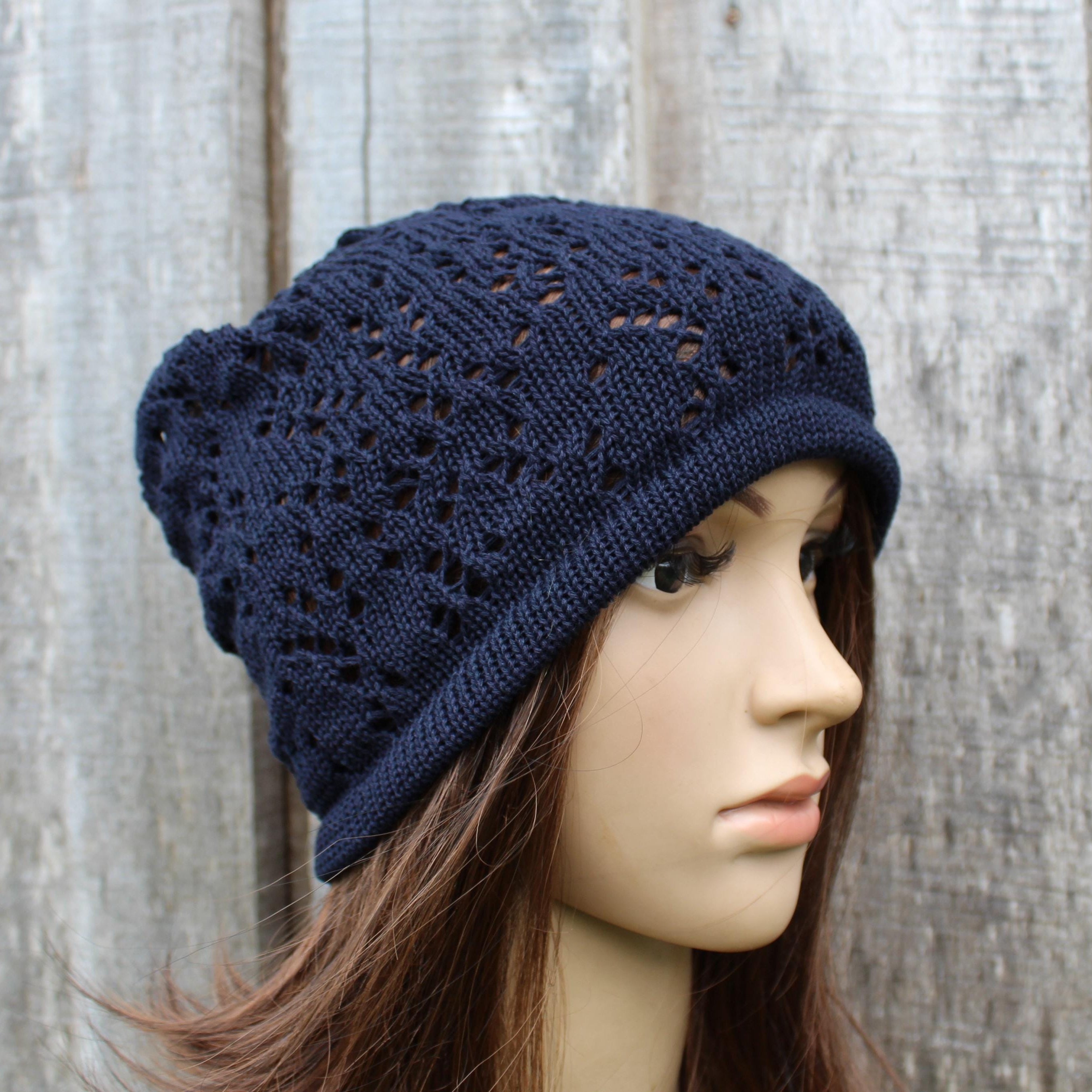 Navy blue knitted hat on a mannequin head against a wooden background