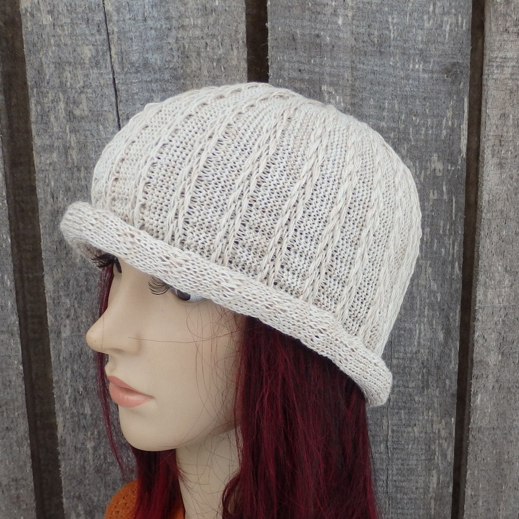 Knitted beige hat on a mannequin head against a wooden background