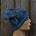 Blue knitted hat with black pattern on a mannequin head against a wooden background