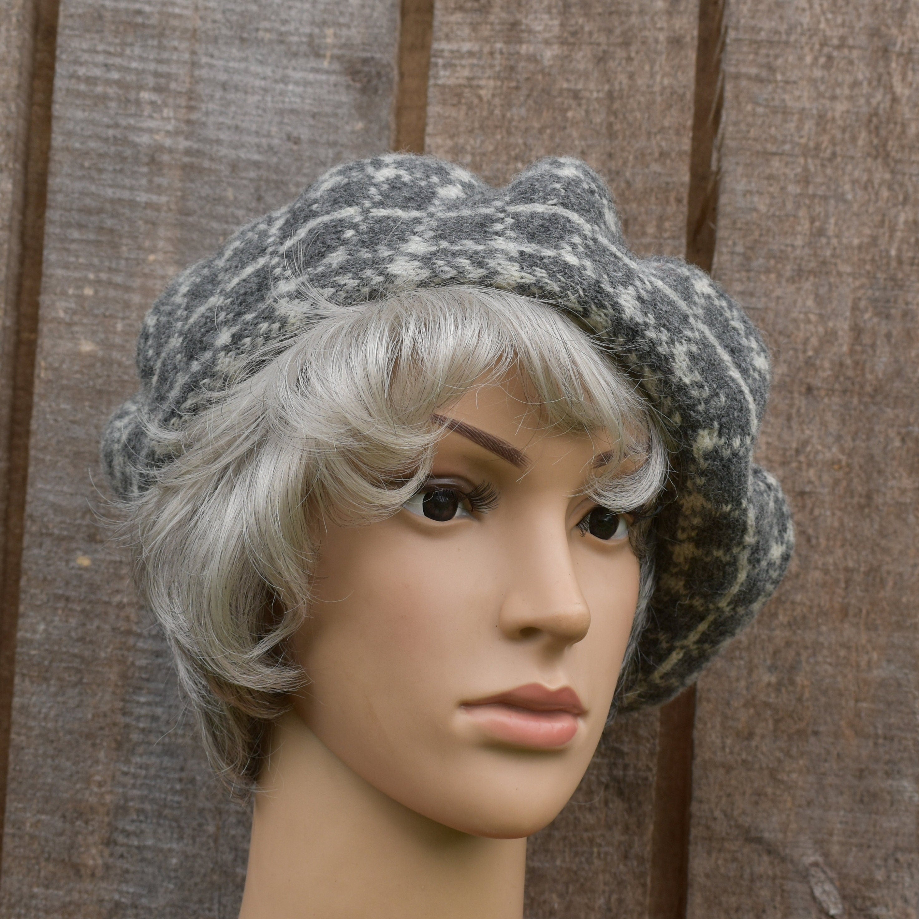 Mannequin head with gray knit hat and white wig against a wooden background