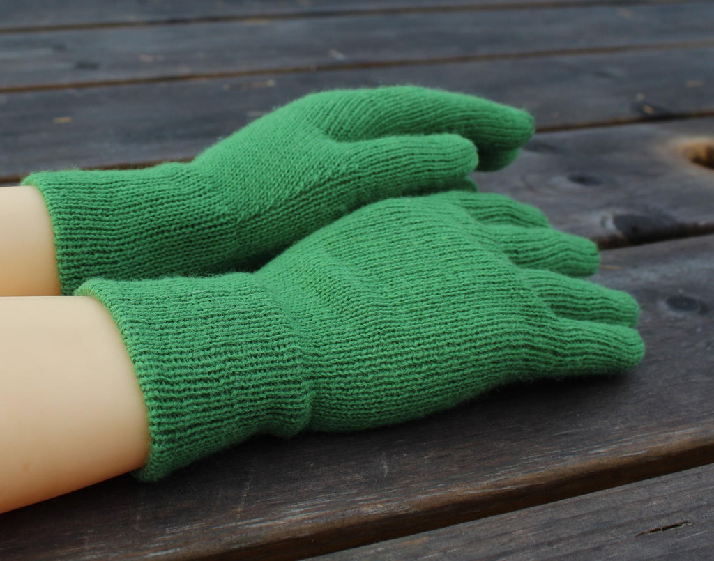 Green merino gloves on a wooden surface
