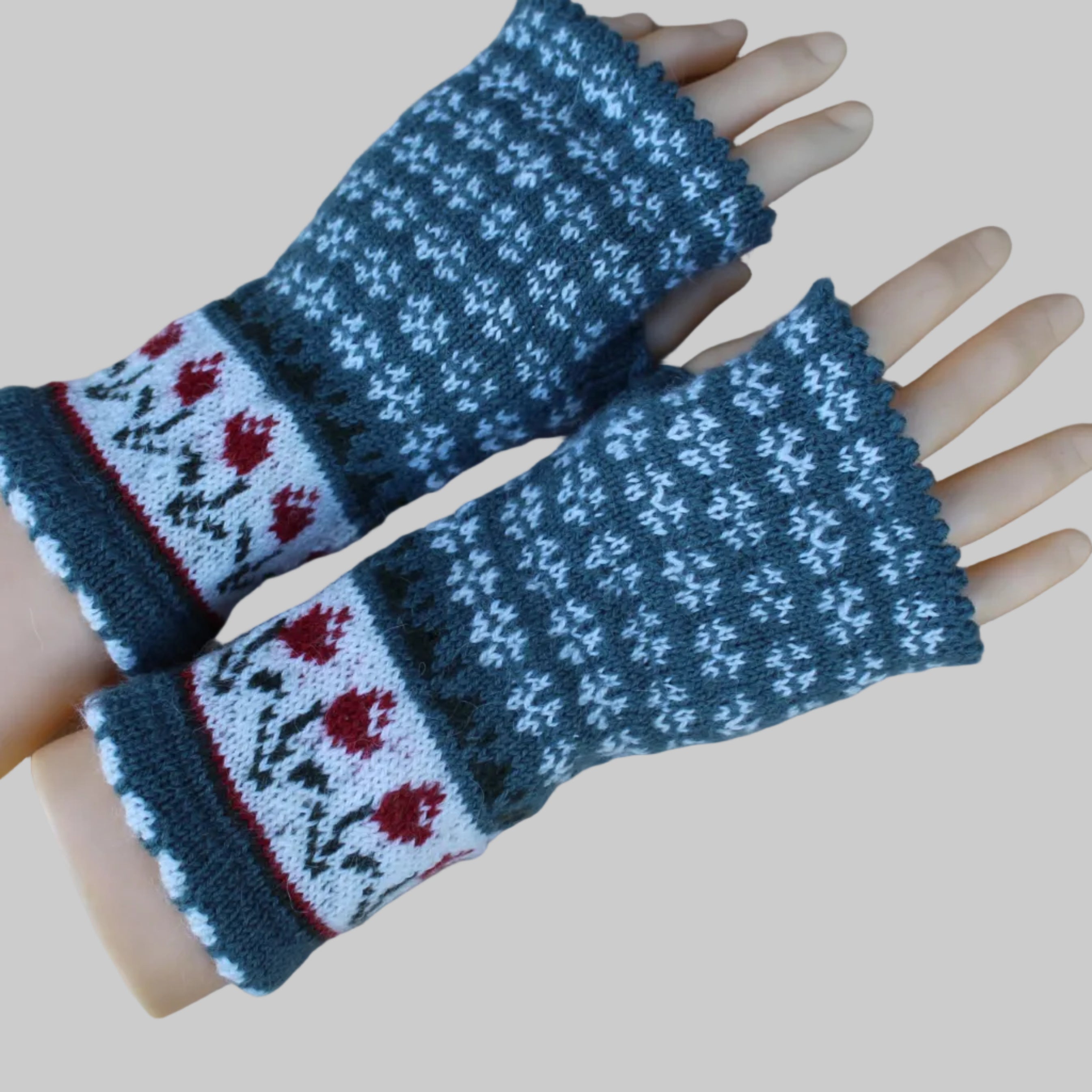 Knitted wrist warmers with floral pattern on a mannequin hand against a wooden background