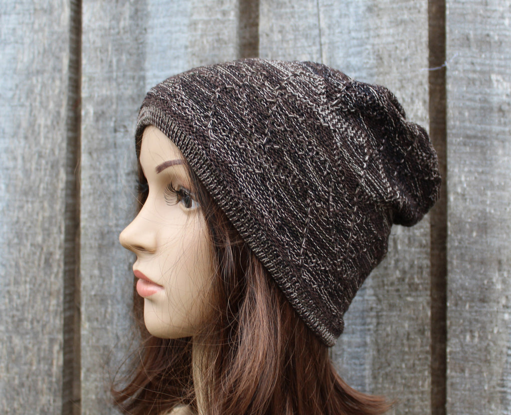 Knitted brown beanie on a mannequin head against a textured wall.