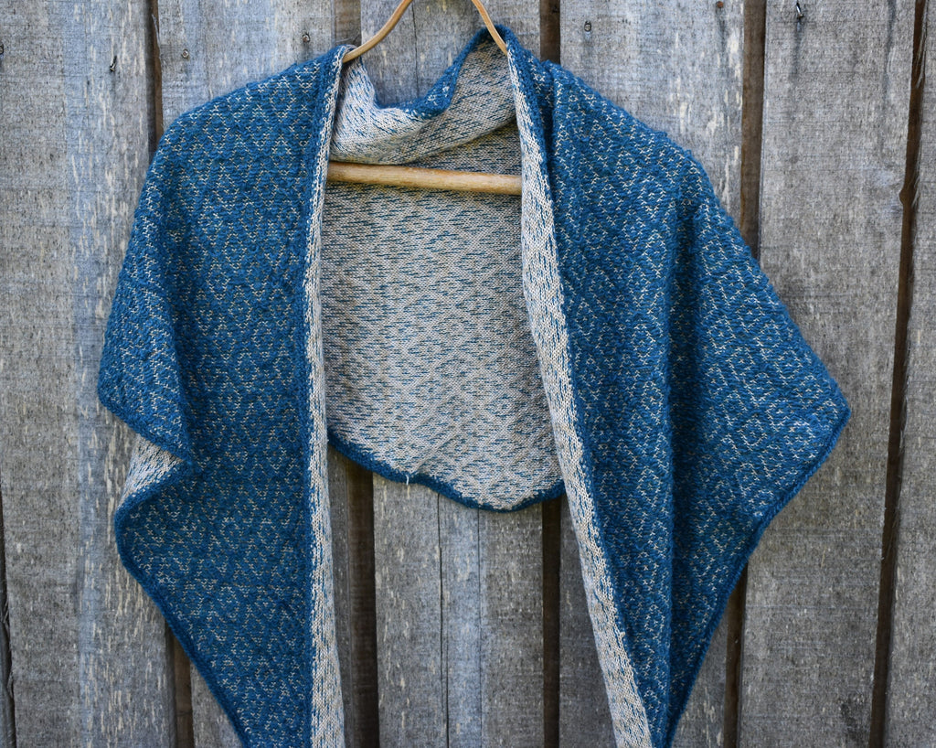 Blue and gray knitted shawl draped over a wooden surface