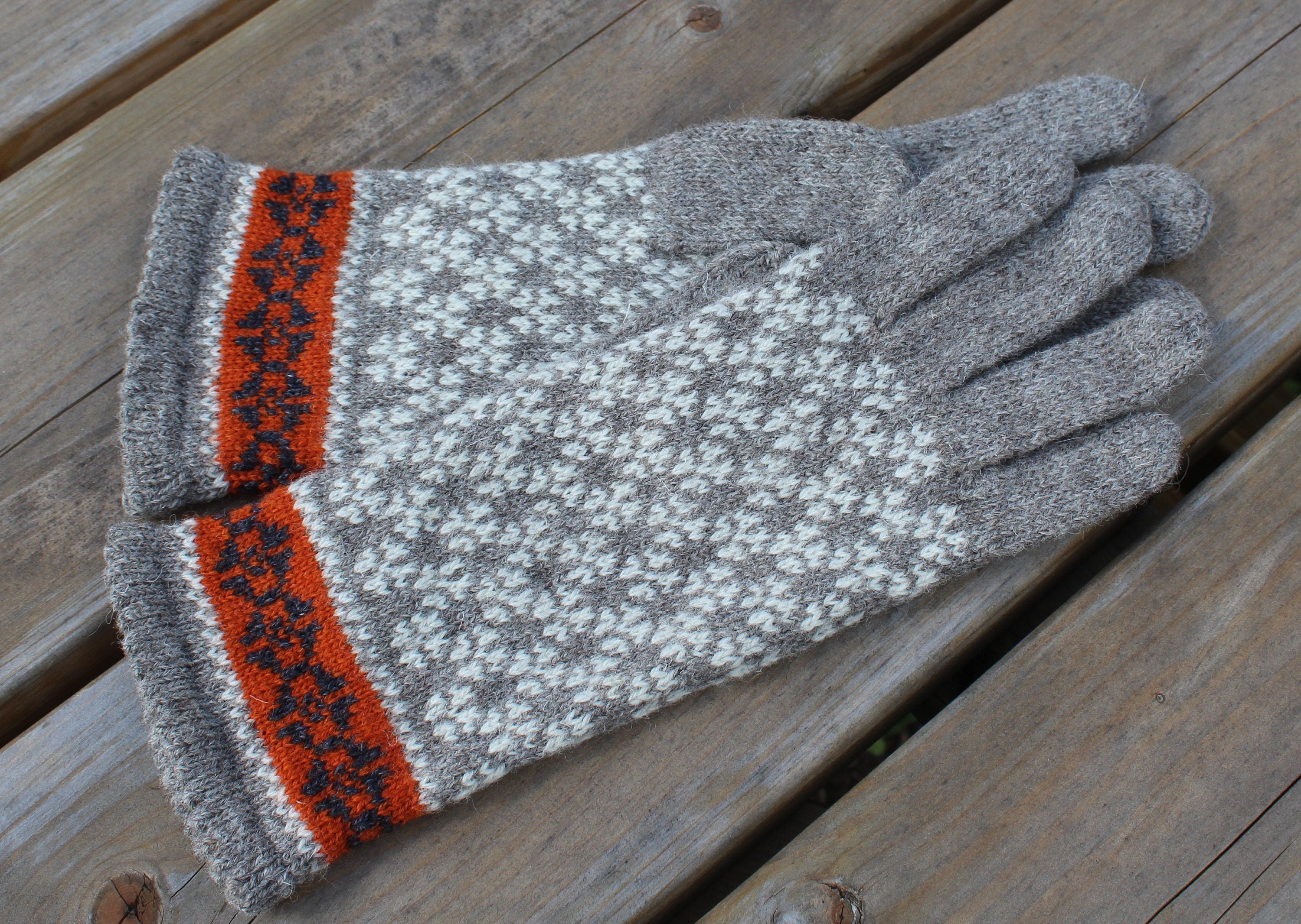 Pair of gloves with a patterned cuff on a wooden surface