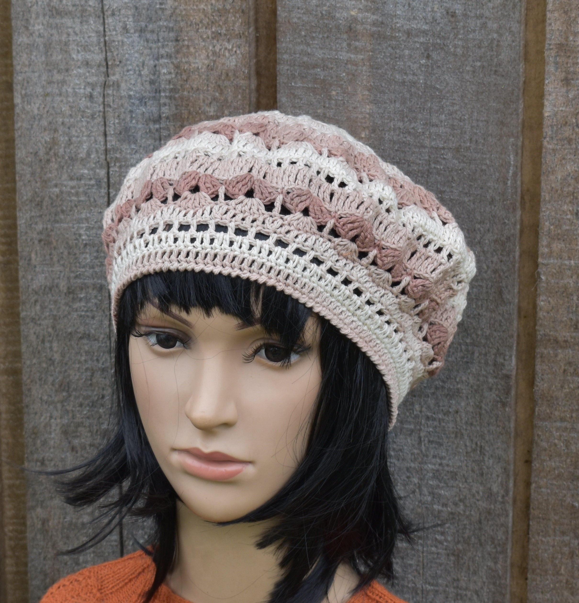 Mannequin head wearing a crocheted beanie with a textured background