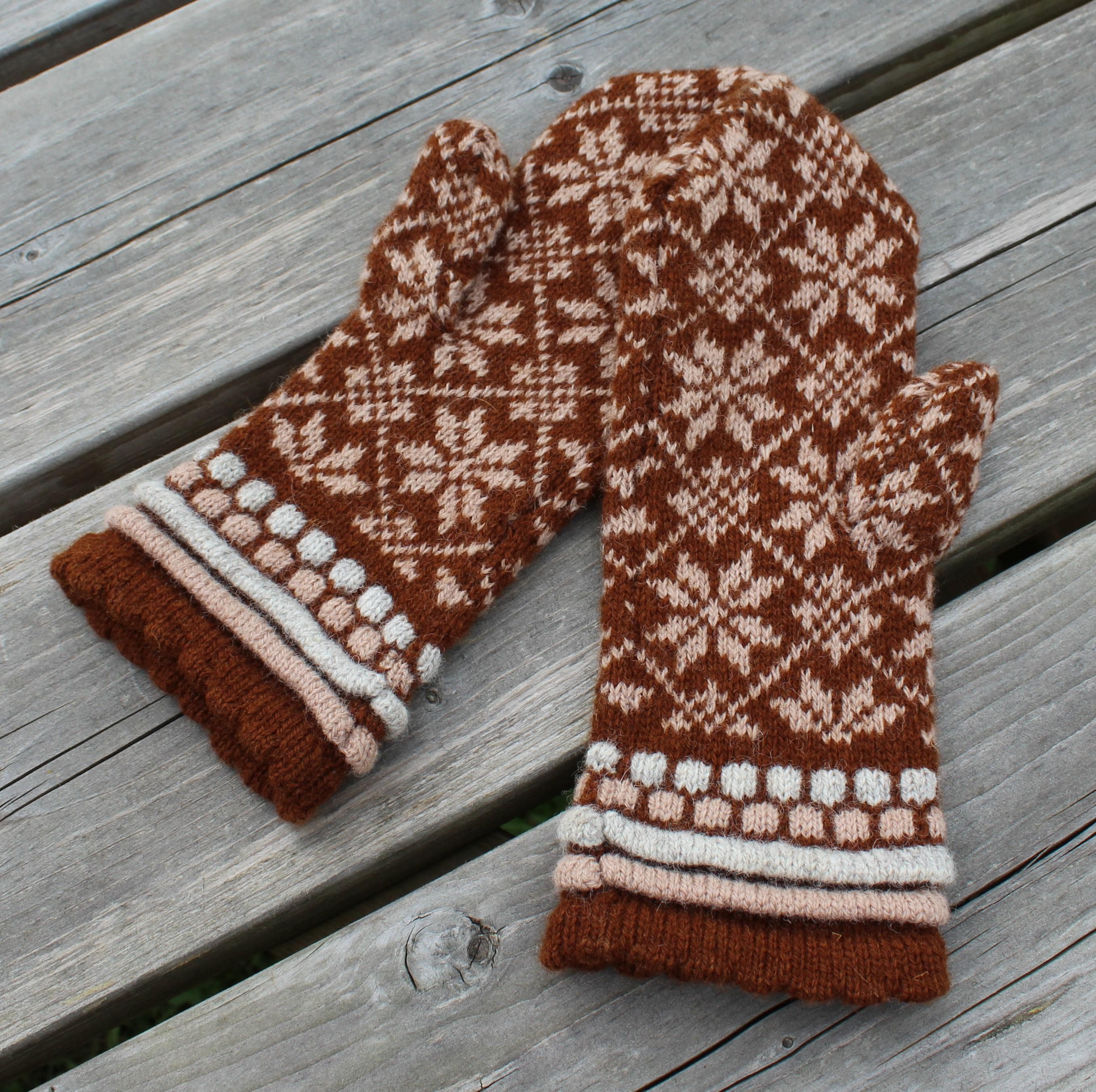 Pair of brown and white patterned mittens on a wooden surface