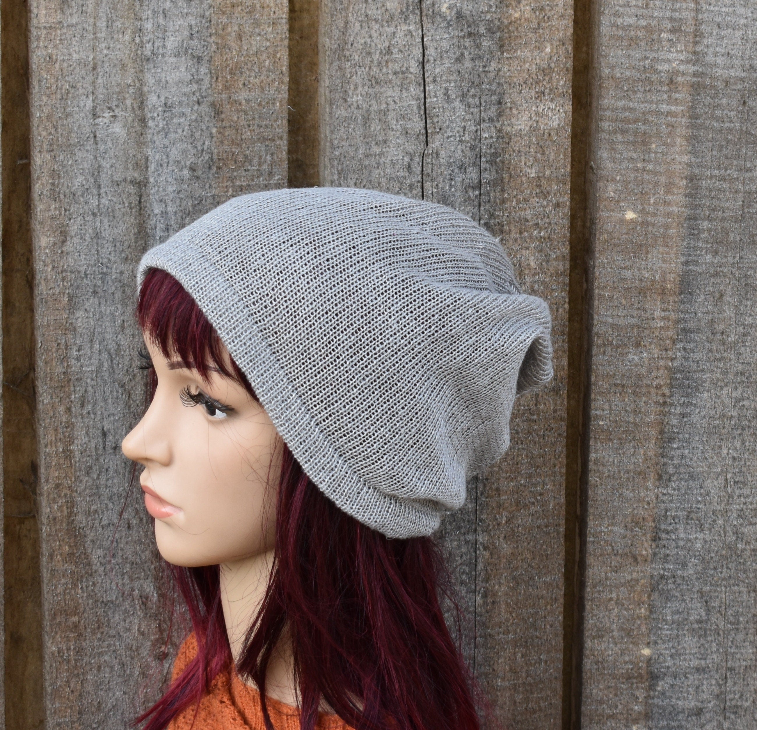 Person wearing a gray knit beanie against a wooden background