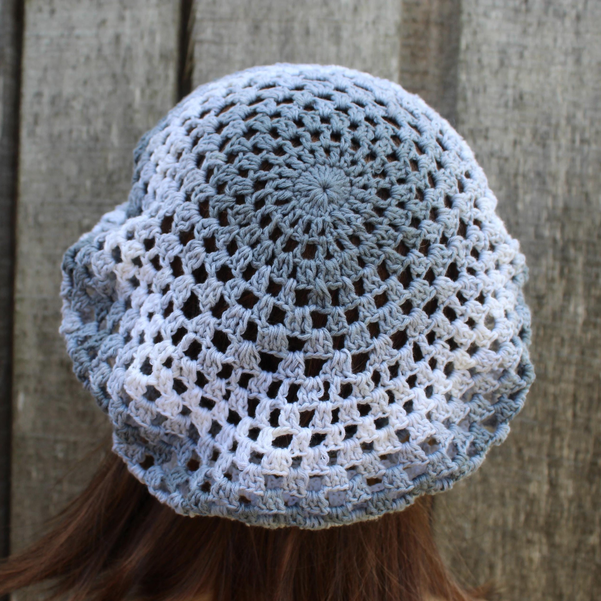 Crocheted blue beanie worn by a person against a wooden background