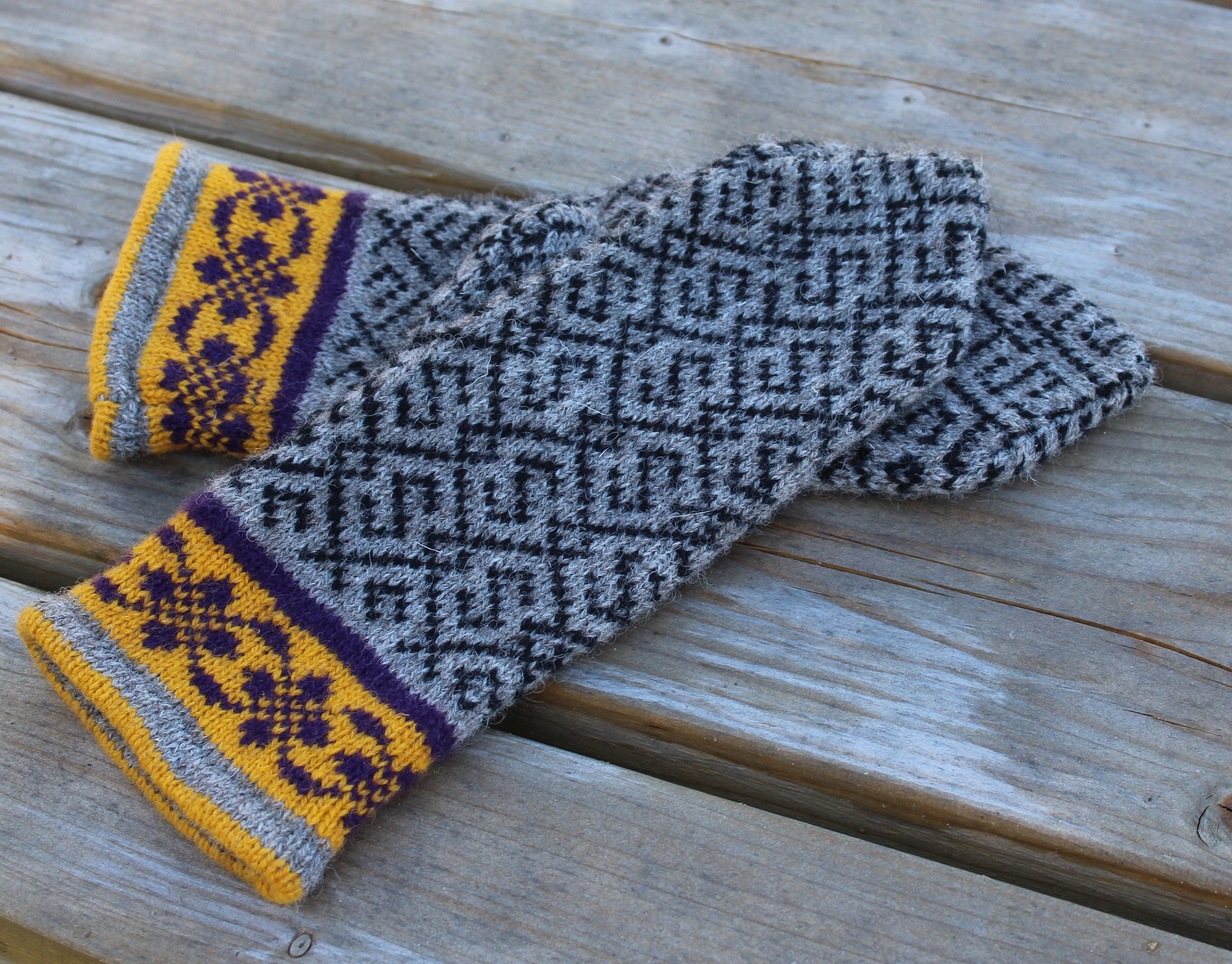 Pair of knitted mittens with a geometric pattern on a wooden surface