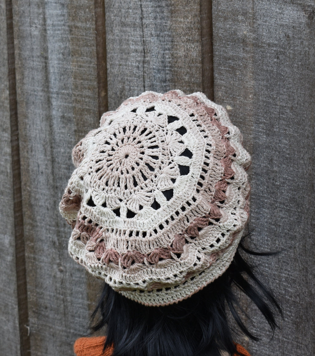 Crocheted hat with a detailed pattern against a wooden background