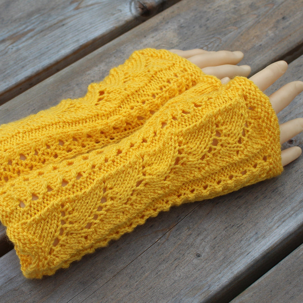 Yellow knitted wrist warmers on a wooden surface
