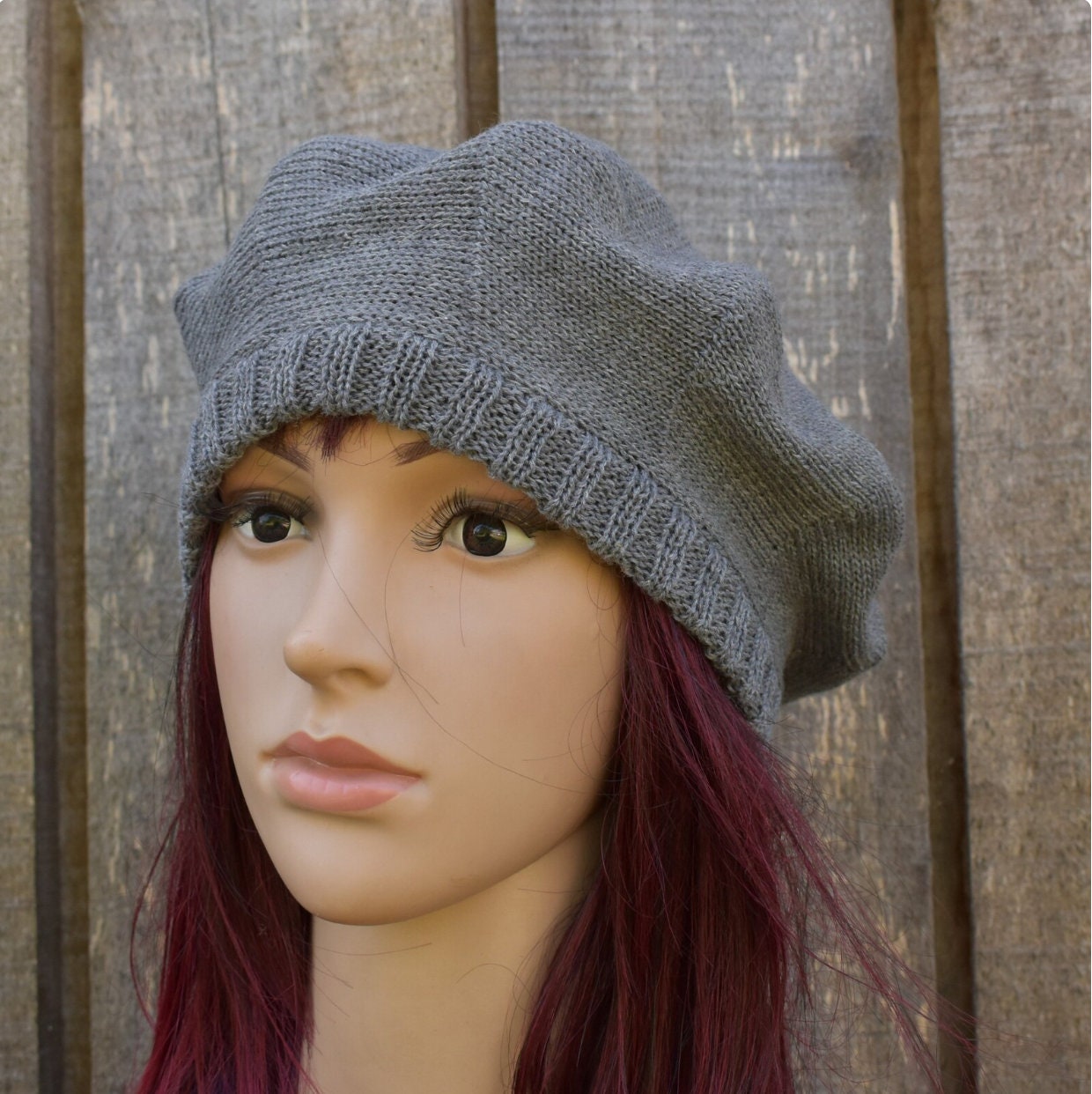 Gray knit beanie on a mannequin head with wooden background